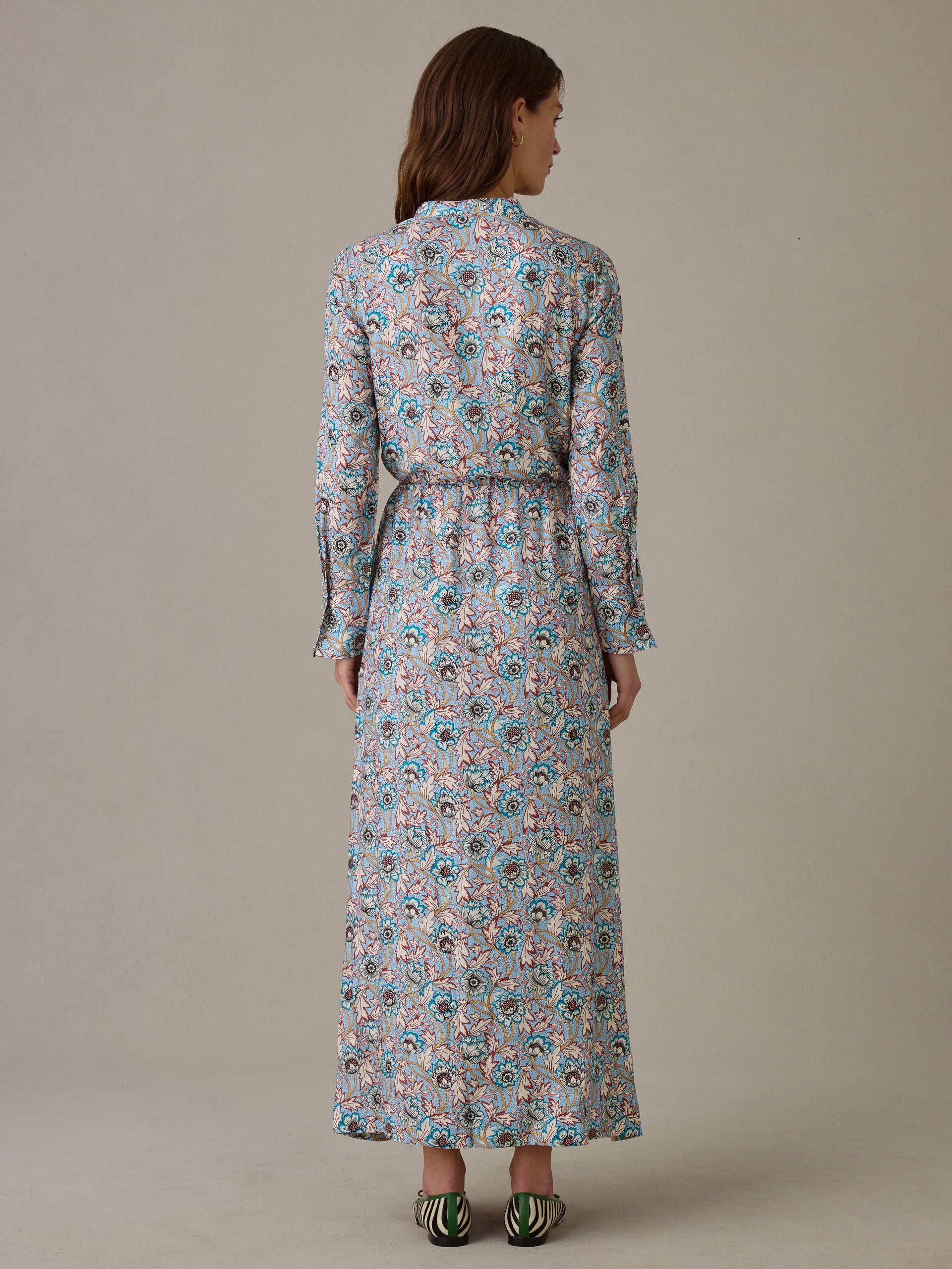 Woman wearing a long-sleeve Hannah Silk Blend Dress in Belle Epoque Bloom by J.McLaughlin, featuring a floral pattern with blue and brown tones, standing against a neutral background.