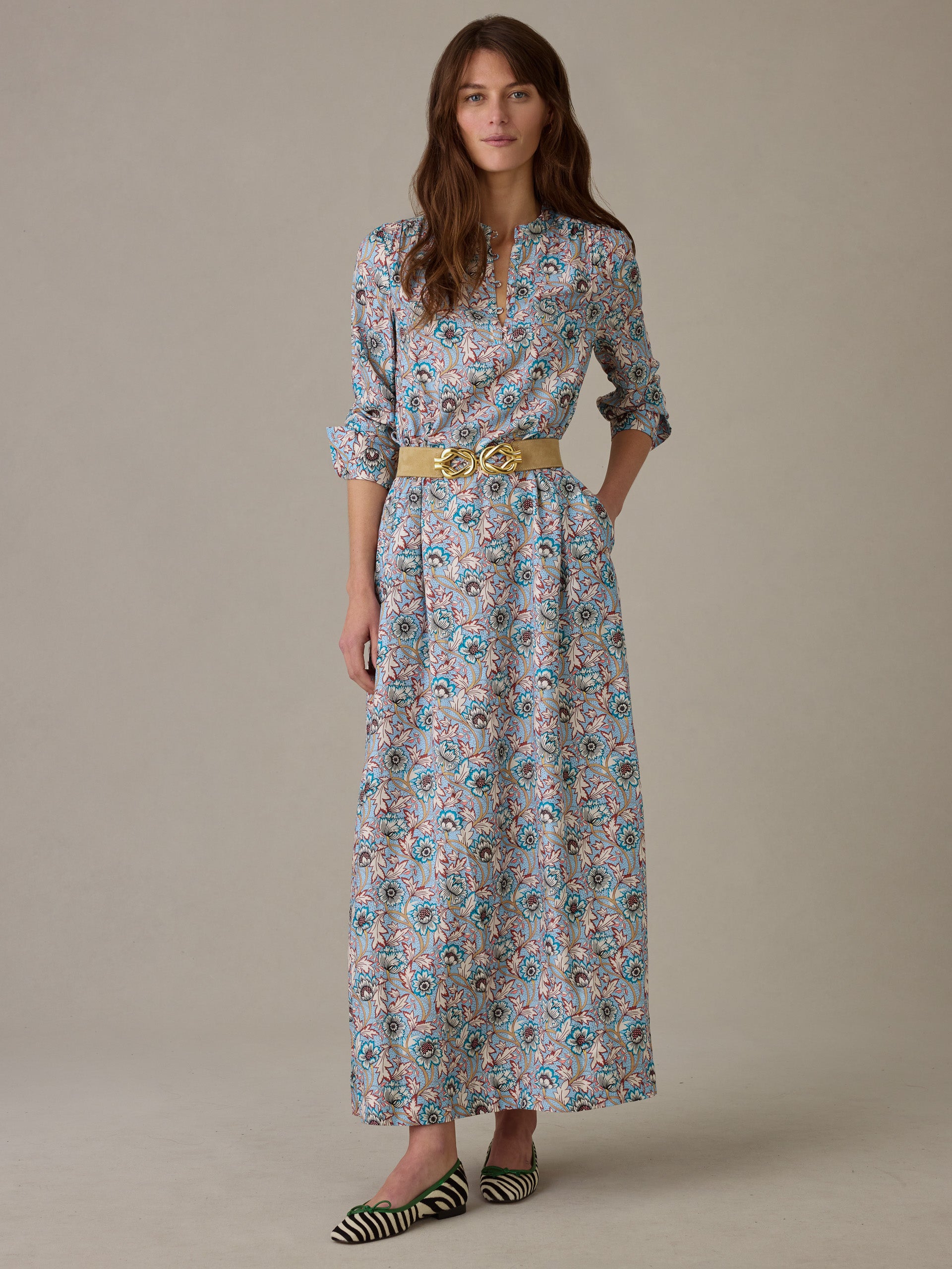 Woman wearing a Hannah Silk Blend Dress in Belle Epoque Bloom by J.McLaughlin, featuring a floral pattern, long sleeves, and a stylish belt, paired with striped flats.