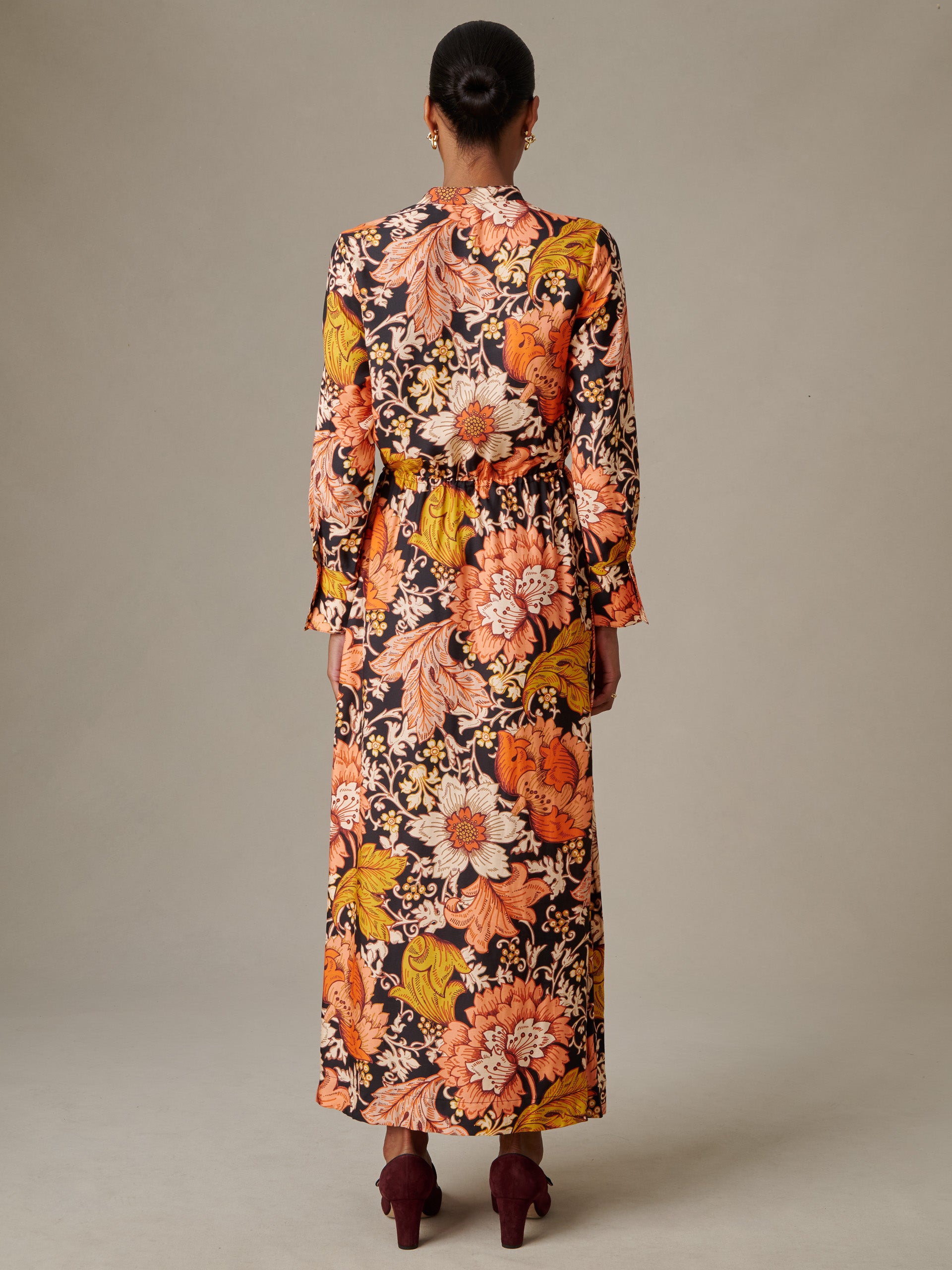 Woman wearing a Hannah Silk Blend Dress in City Garden by J.McLaughlin, featuring a vibrant floral pattern in warm autumn colors and a flowing long-sleeve silhouette.