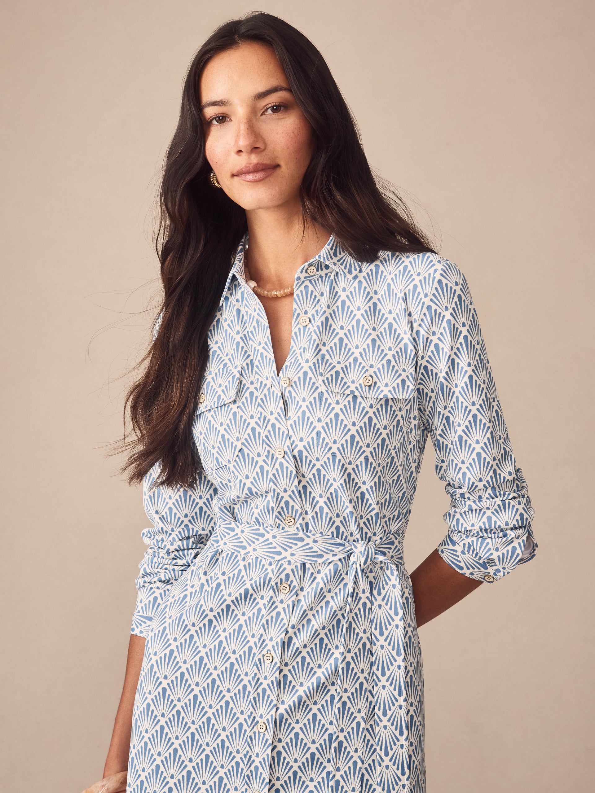 Woman wearing the Haarlem Dress in Sandshell by J.McLaughlin, featuring an elegant blue and off-white pattern with a belted waist and classic collar, embodying effortlessly stylish, enduring designs and innovative fabrics. A destination for defining style. Life, Well-Lived.