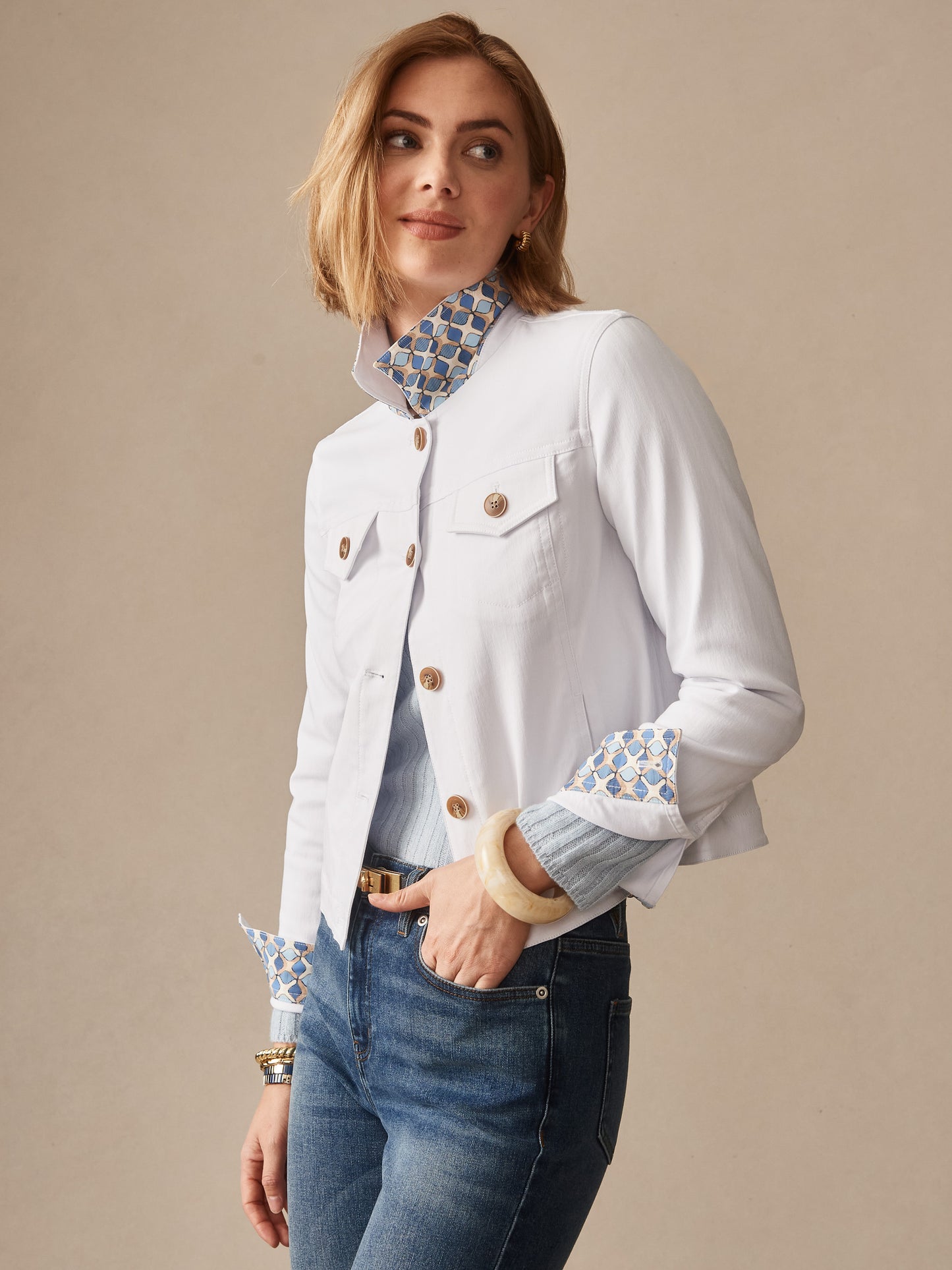 Woman wearing a white Haven Jacket by J.McLaughlin featuring patterned collar and cuffs, paired with blue jeans, embodying effortlessly stylish, enduring designs and innovative fabrics.