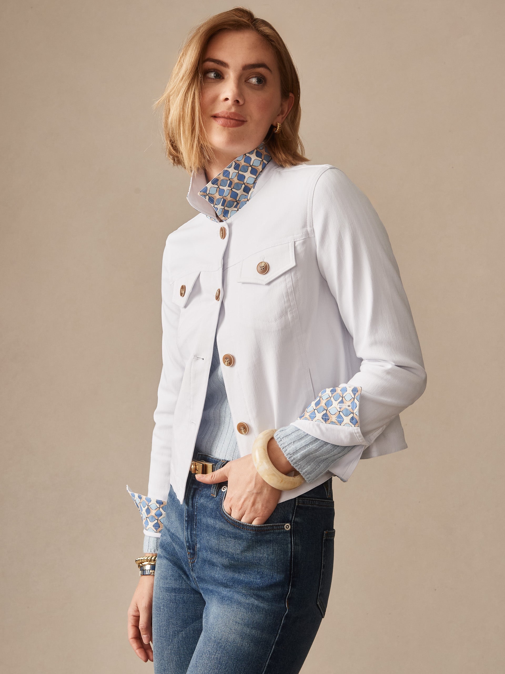 Woman wearing a white Haven Jacket by J.McLaughlin featuring patterned collar and cuffs, paired with blue jeans, embodying effortlessly stylish, enduring designs and innovative fabrics.