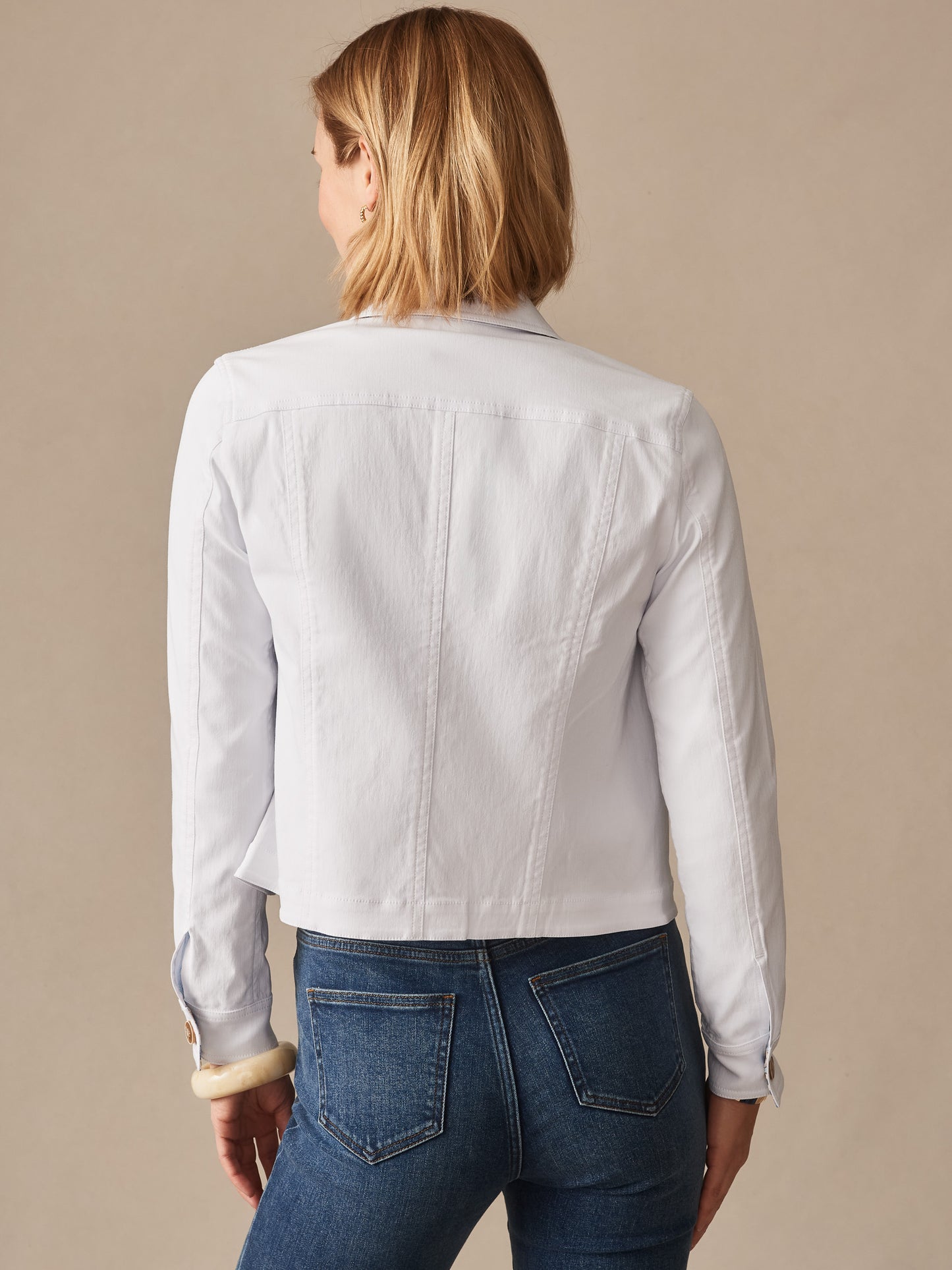Woman wearing a white Haven Jacket by J.McLaughlin, showcasing effortlessly stylish design and enduring fabrics, perfect for a legacy of timeless fashion and defining style. Life, Well-Lived.