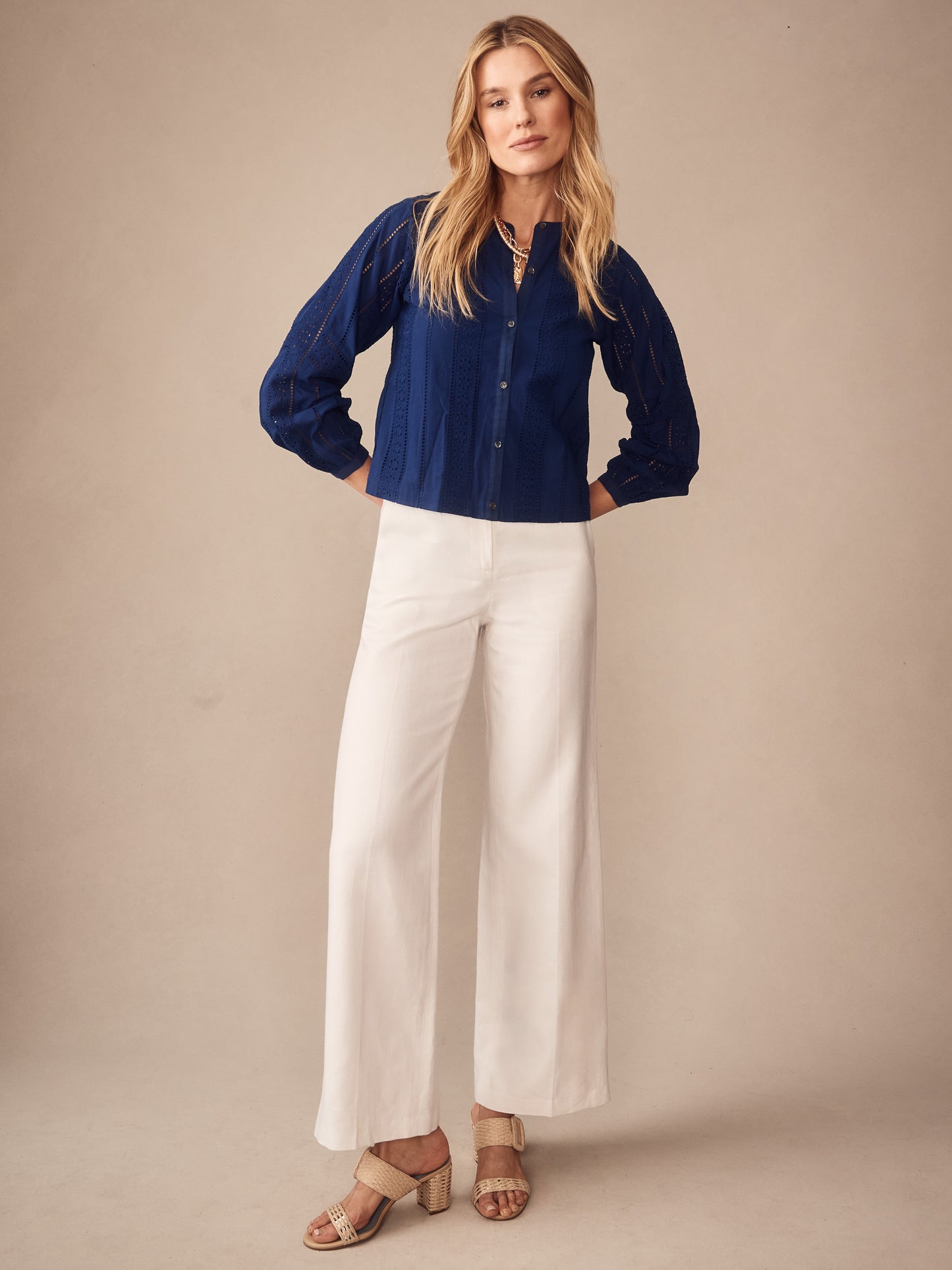 Woman wearing a navy Hazel Blouse in Eyelet by J.McLaughlin paired with white wide-leg pants and beige sandals, showcasing effortlessly stylish, enduring designs for a destination for defining style. Life, Well-Lived.