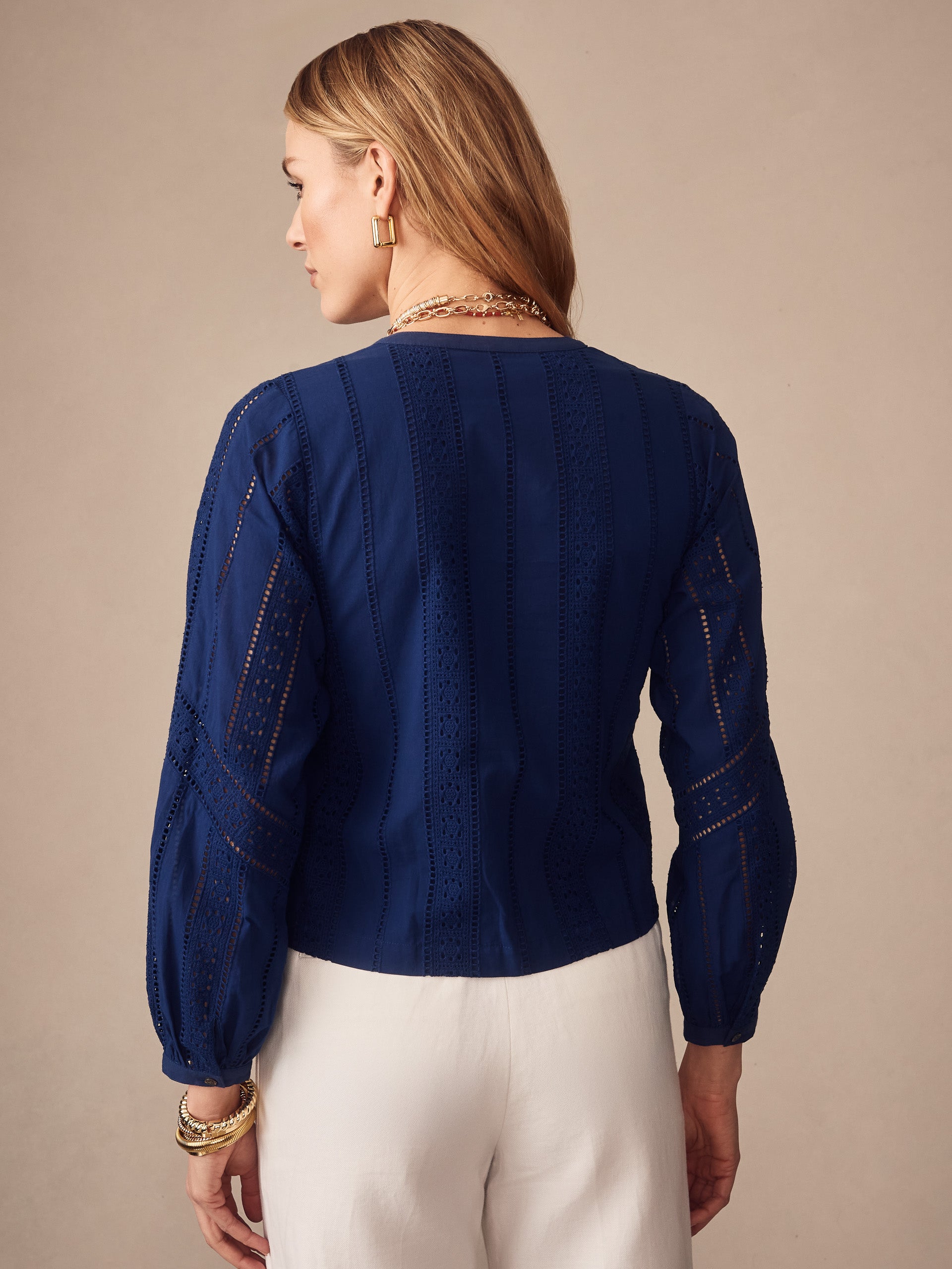 Woman wearing a navy Hazel Blouse in Eyelet by J.McLaughlin, featuring delicate eyelet patterns and long sleeves, embodying effortlessly stylish, enduring designs.