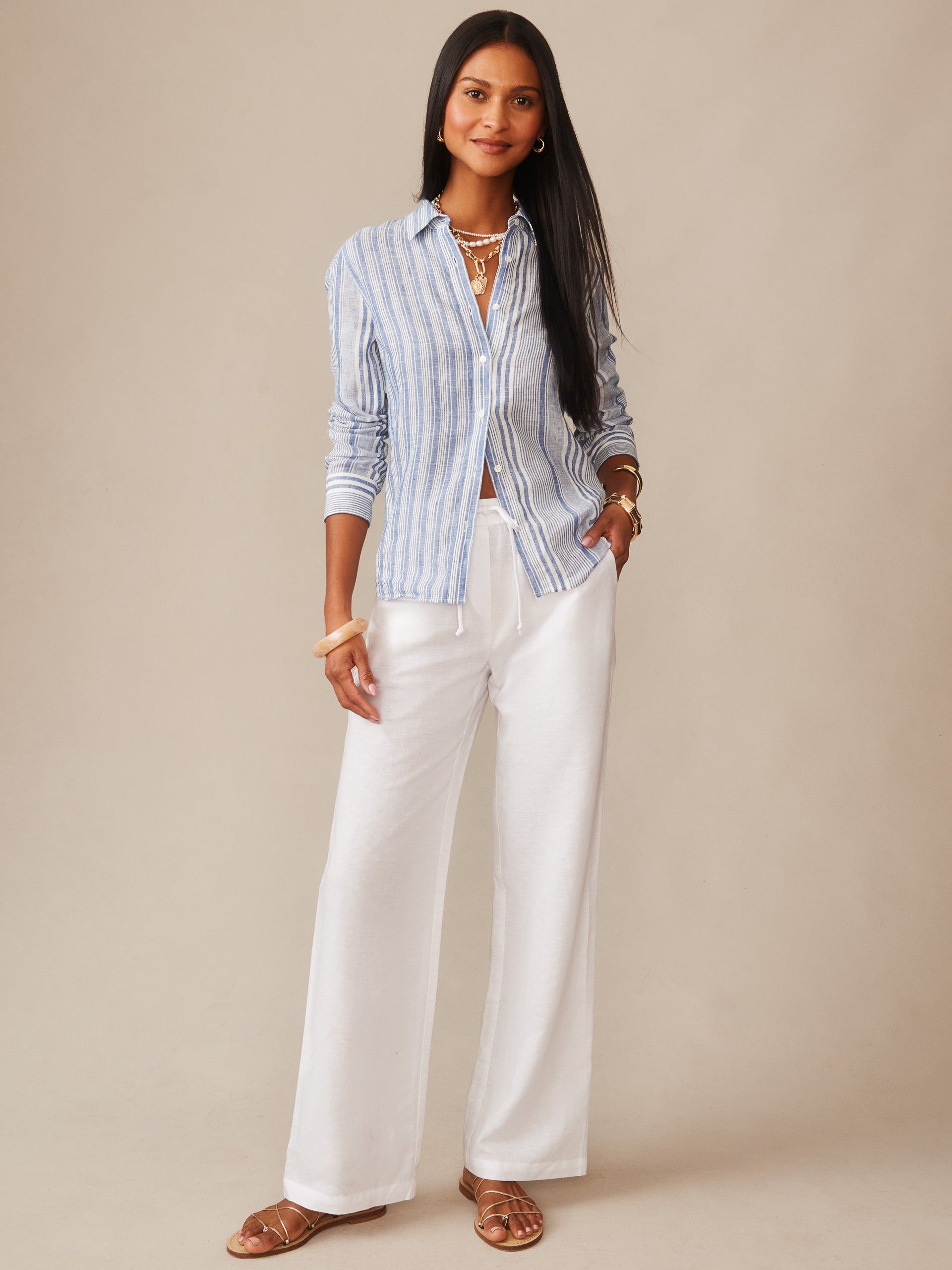 Woman wearing J.McLaughlin Irene Linen Pants in white with a blue and white striped shirt, embodying effortlessly stylish comfort and enduring designs in a timeless fashion look.