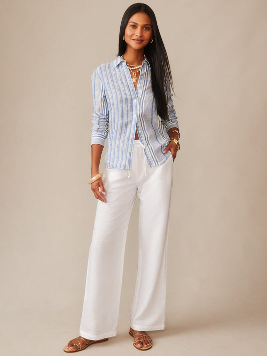 Woman wearing J.McLaughlin Irene Linen Pants in white with a blue and white striped shirt, embodying effortlessly stylish comfort and enduring designs in a timeless fashion look.
