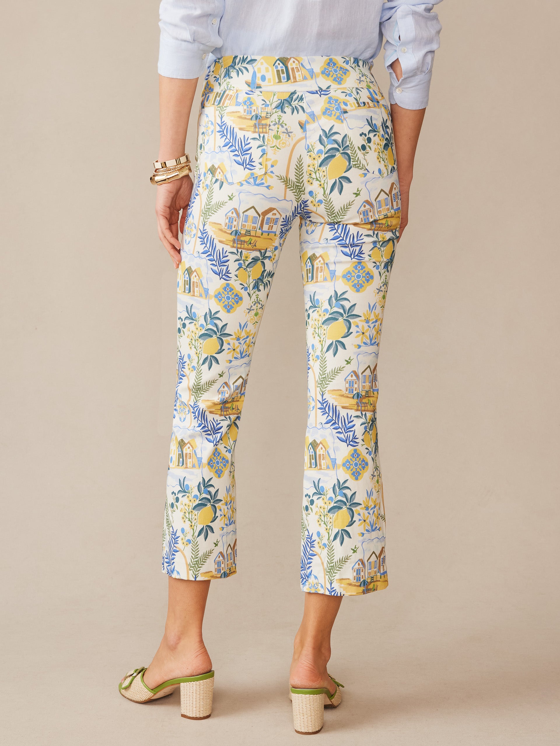 Back view of a person wearing J.McLaughlin Ivy Pants in Amalfi Coast, featuring a vibrant off-white base with blue and yellow coastal-inspired prints, embodying effortlessly stylish, enduring designs and innovative fabrics. A destination for defining style. Life, Well-Lived.