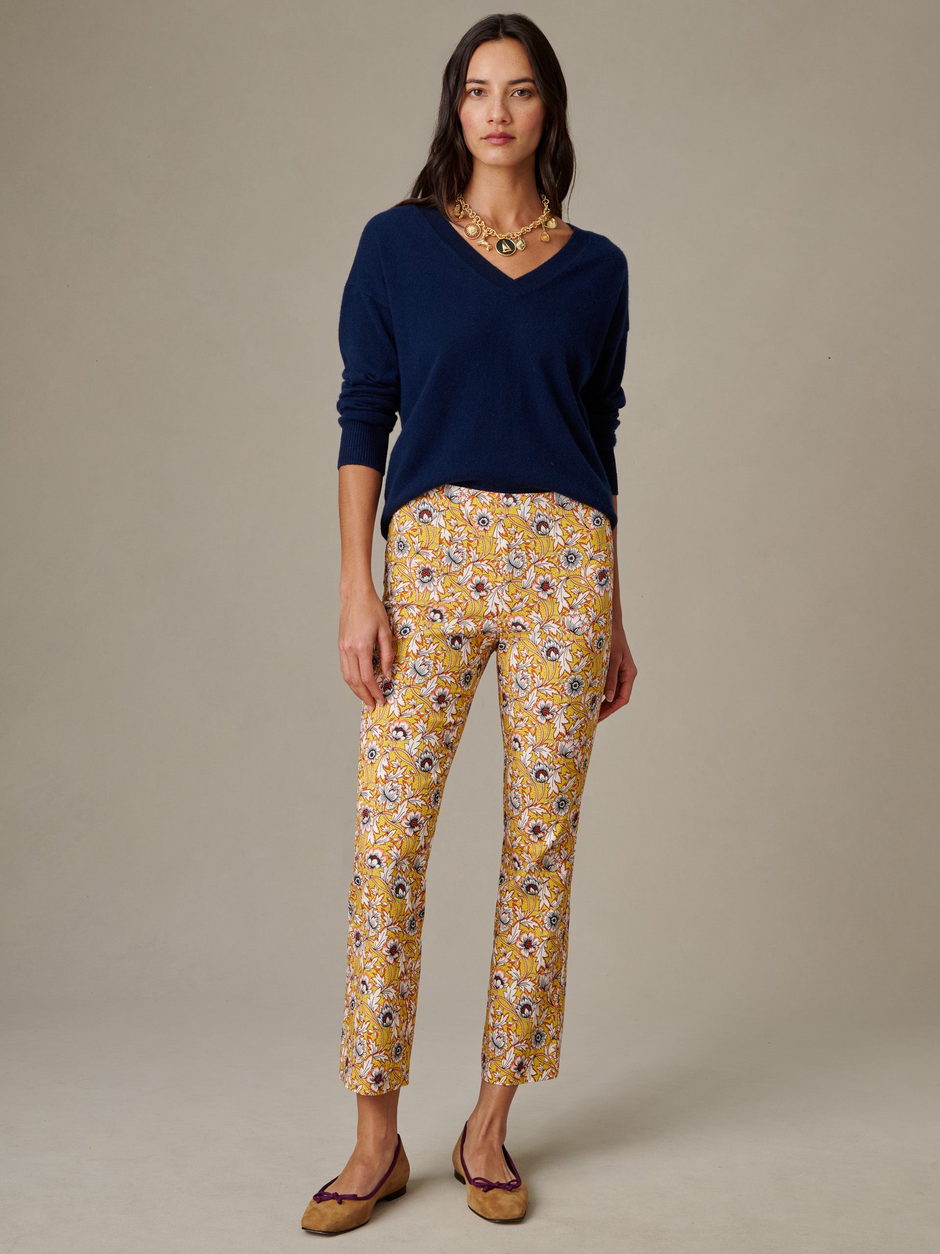 Woman wearing J.McLaughlin Ivy Pants in Belle Epoque Bloom with a navy V-neck sweater and brown flats, showcasing effortlessly stylish and enduring designs.