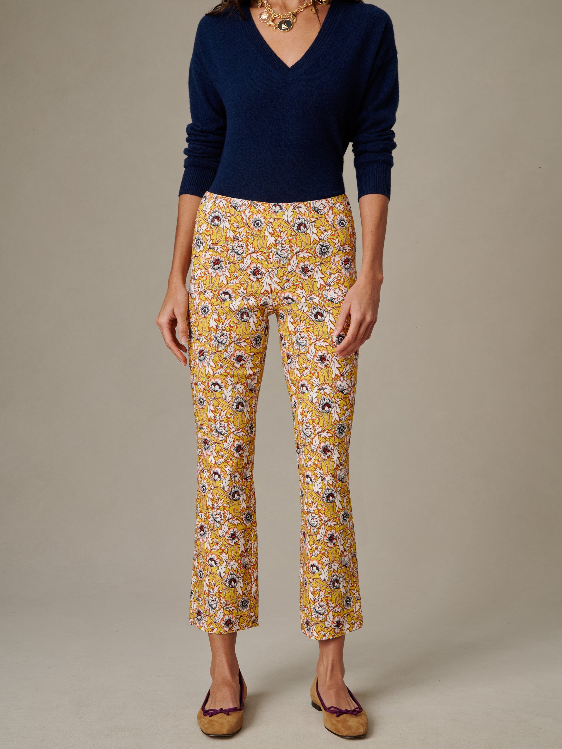 Front view of a woman wearing J.McLaughlin Ivy Pants in Belle Epoque Bloom with a navy blue V-neck sweater and tan flats, showcasing an effortlessly stylish and timeless look.