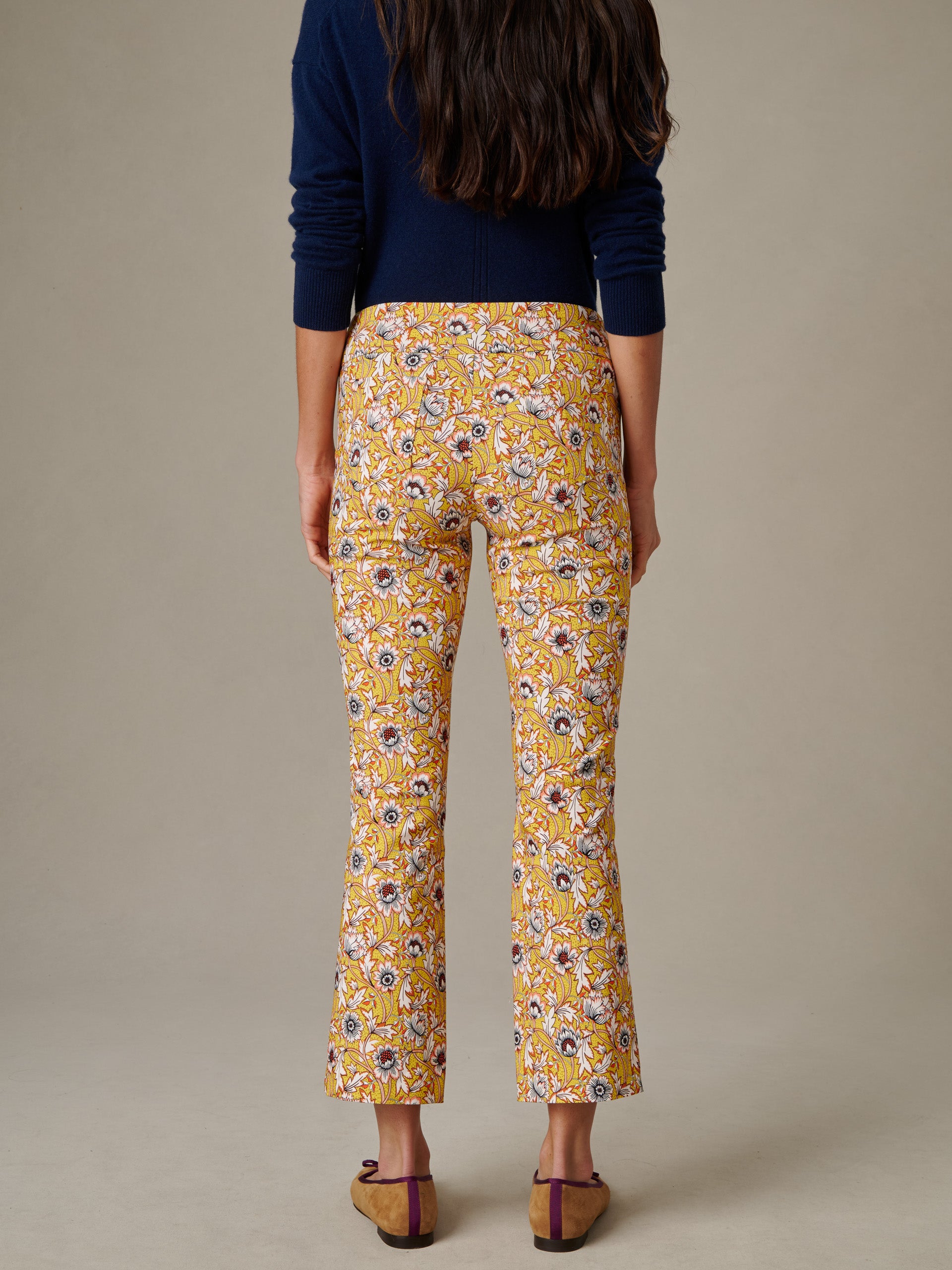 Woman wearing Ivy Pants in Belle Epoque Bloom with a floral print, paired with a navy sweater and brown flats, showcasing J.McLaughlin’s effortlessly stylish and enduring design.