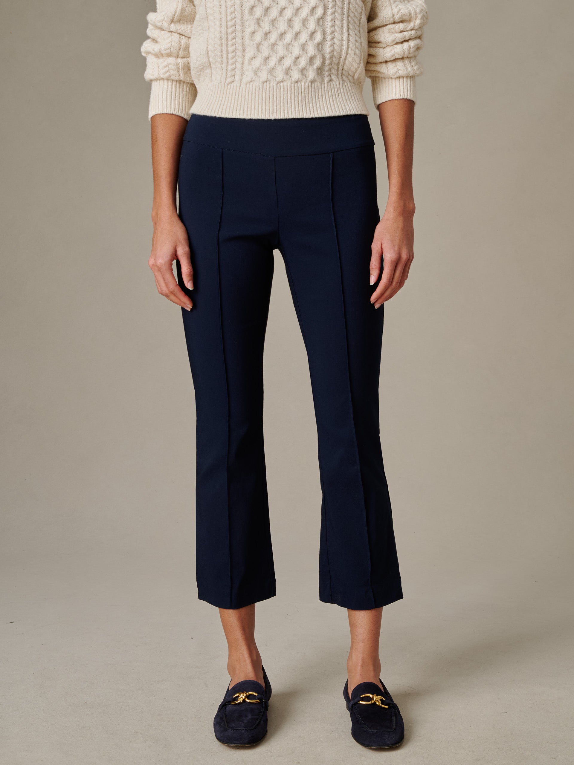 Woman wearing navy Ivy Pants by J.McLaughlin paired with a cream cable knit sweater and navy loafers, showcasing an effortlessly stylish and timeless look.