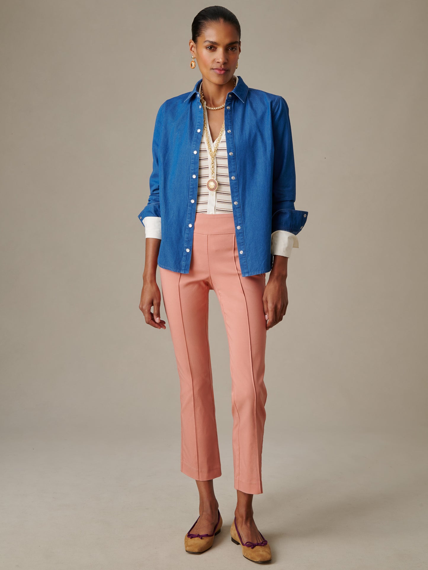 Woman wearing pink Ivy Pants by J.McLaughlin paired with a blue button-up shirt and beige flats, showcasing effortlessly stylish, enduring designs from a legacy of timeless fashion.