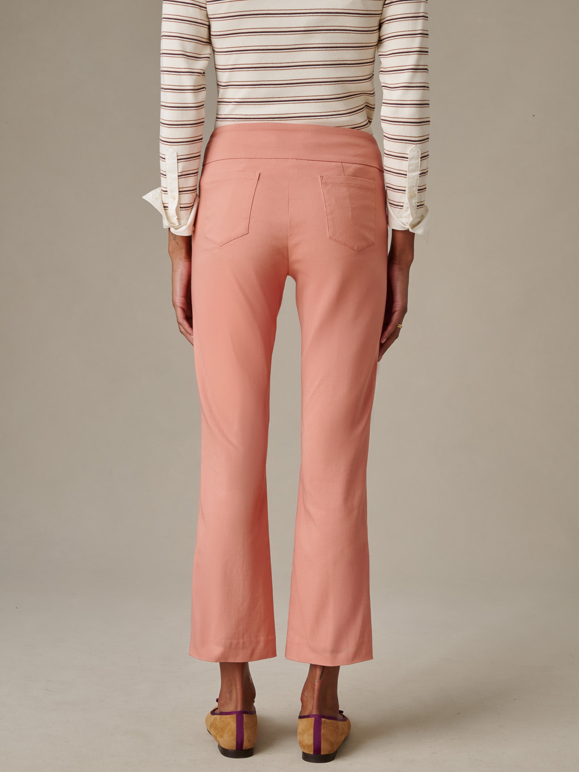 Back view of a woman wearing peach-colored Ivy Pants by J.McLaughlin paired with a striped long-sleeve top, showcasing impeccable craftsmanship and timeless style.