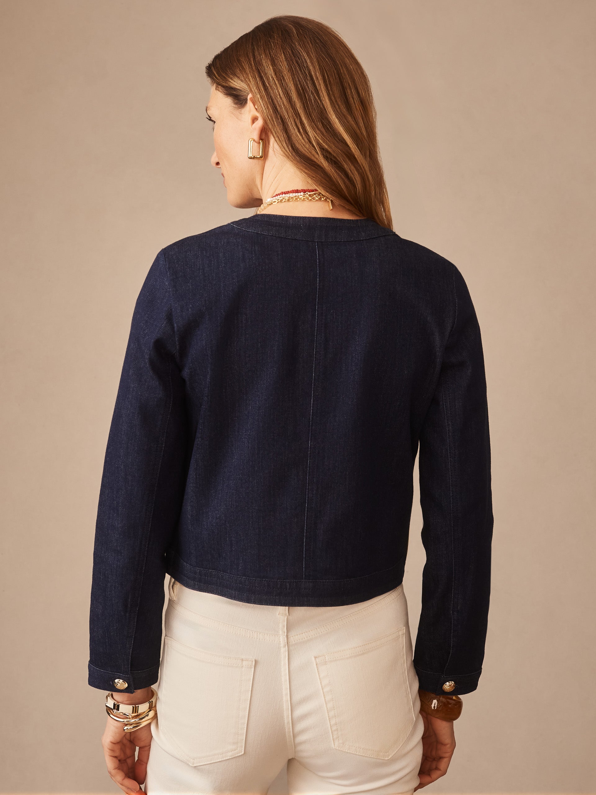 Woman wearing a Jackie Denim Jacket by J.McLaughlin in a classic indigo denim, paired with white pants, showcasing effortlessly stylish and enduring designs from a destination for defining style. Life, Well-Lived.