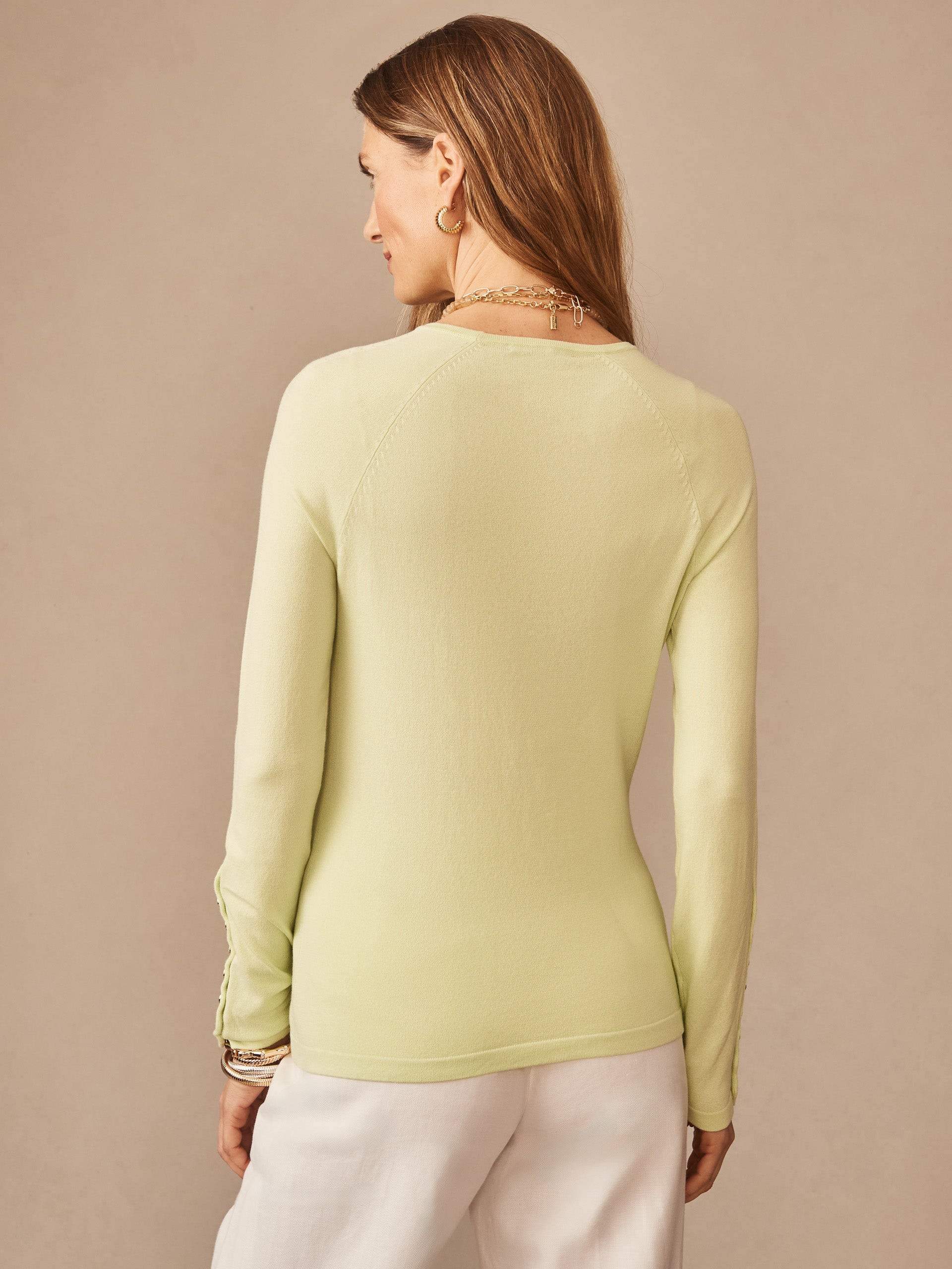 A woman wearing a lime green Jamey Sweater by J.McLaughlin, showcasing effortlessly stylish, enduring designs crafted with innovative fabrics for a legacy of timeless fashion.