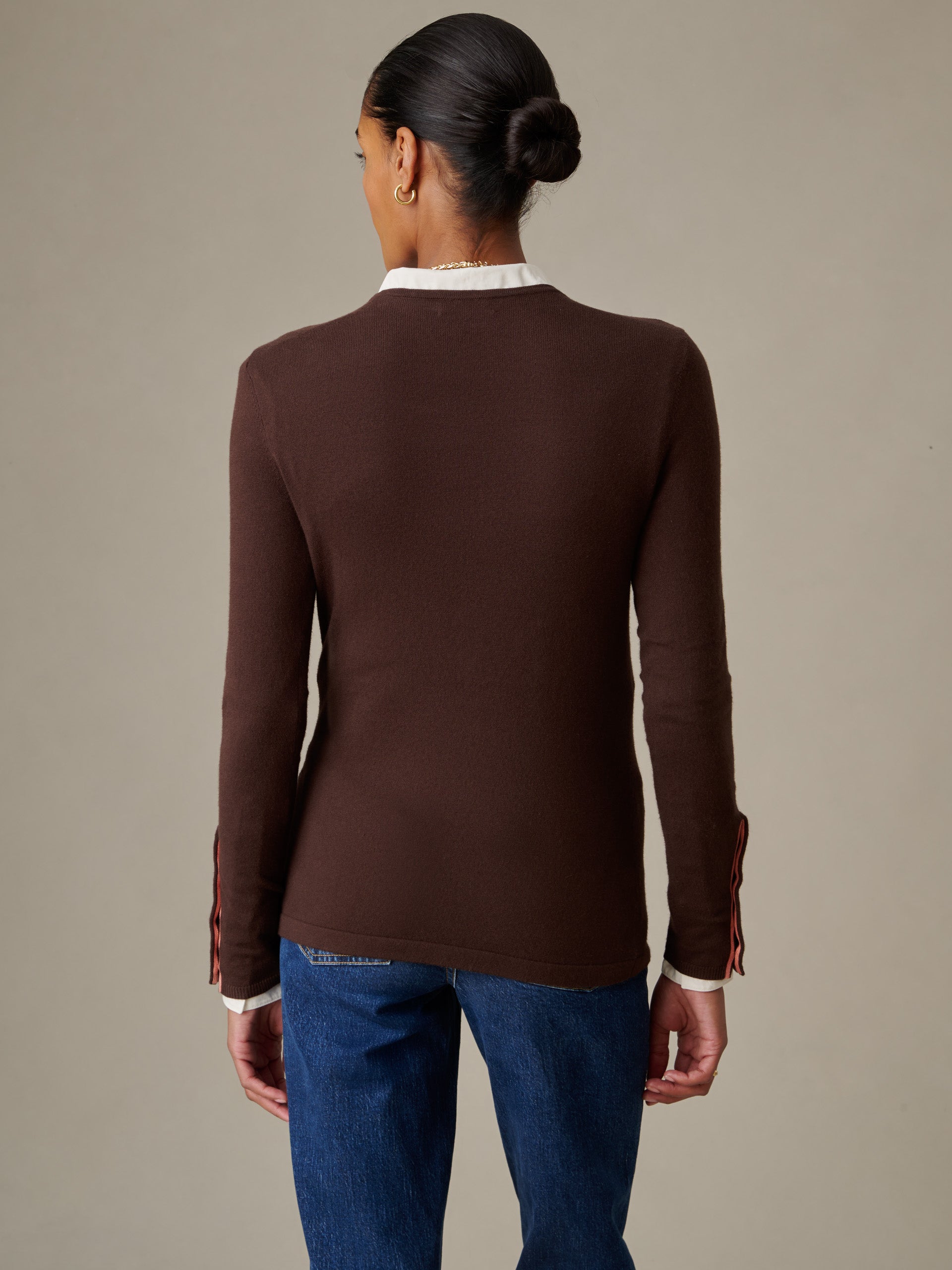 A woman seen from the back wearing a brown Jamey Sweater by J.McLaughlin, paired with blue jeans, showcasing the sweater’s sleek fit and timeless, effortlessly stylish design.