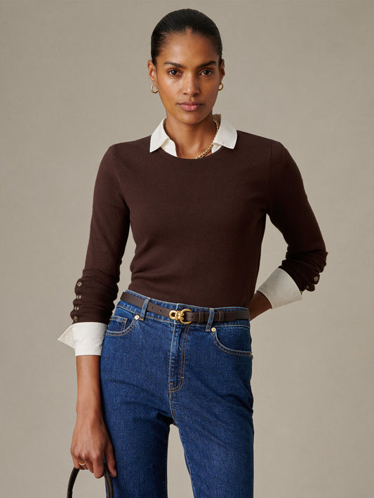 Woman wearing a brown Jamey Sweater from J.McLaughlin layered over a white collared shirt paired with blue jeans and a dark belt, showcasing timeless, effortlessly stylish fashion.