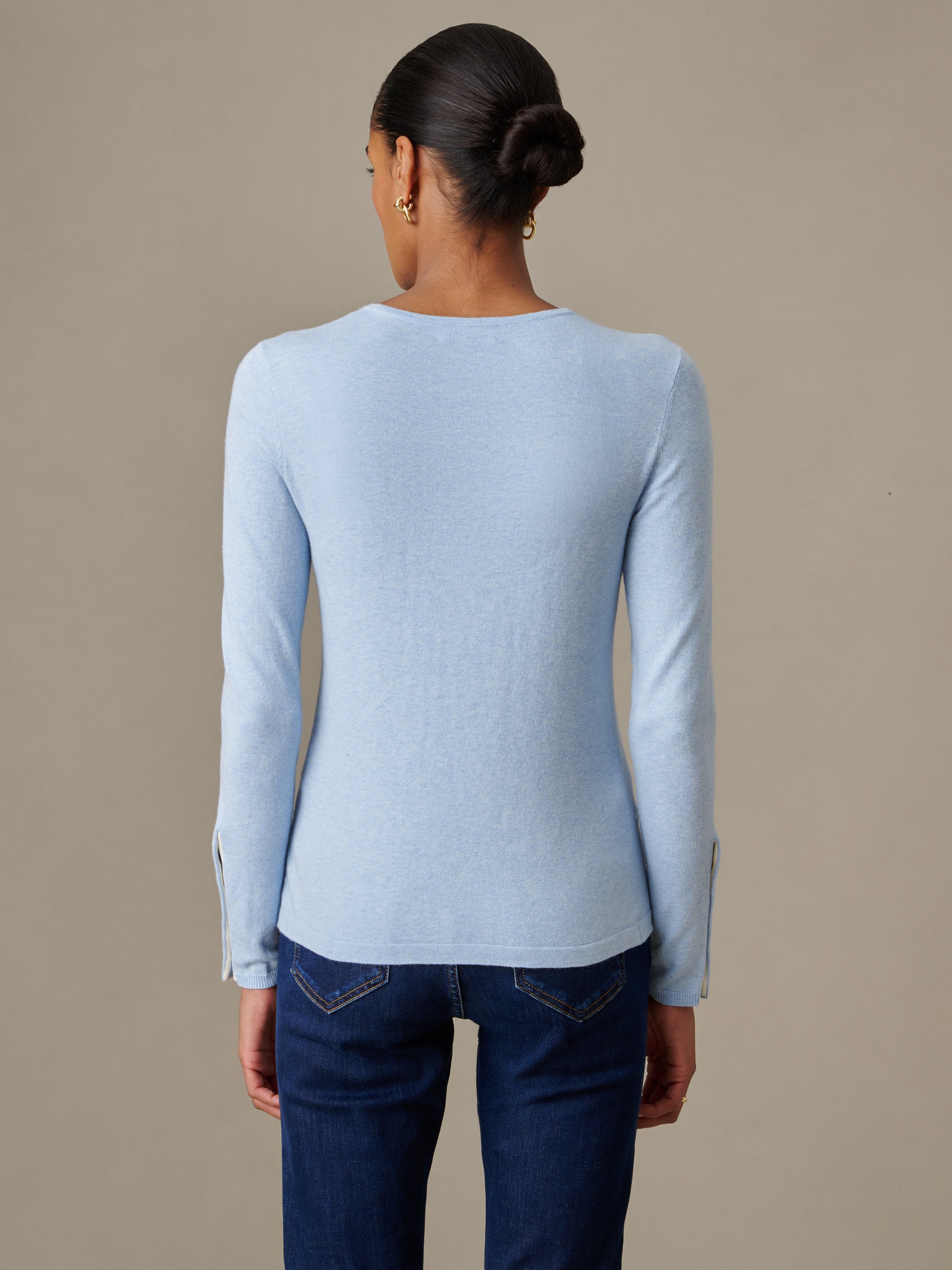 Back view of a woman wearing a light blue Jamey Sweater by J.McLaughlin paired with dark denim jeans, showcasing the sweater’s sleek, timeless design and fine craftsmanship.