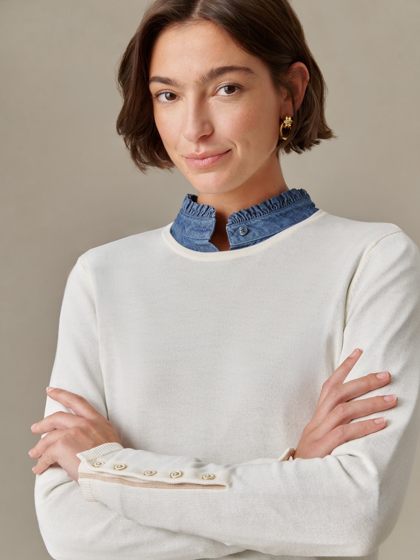 Woman wearing a cream Jamey Sweater by J.McLaughlin with button details on the sleeve and a ruffled blue collar underneath, showcasing timeless, effortlessly stylish layering.