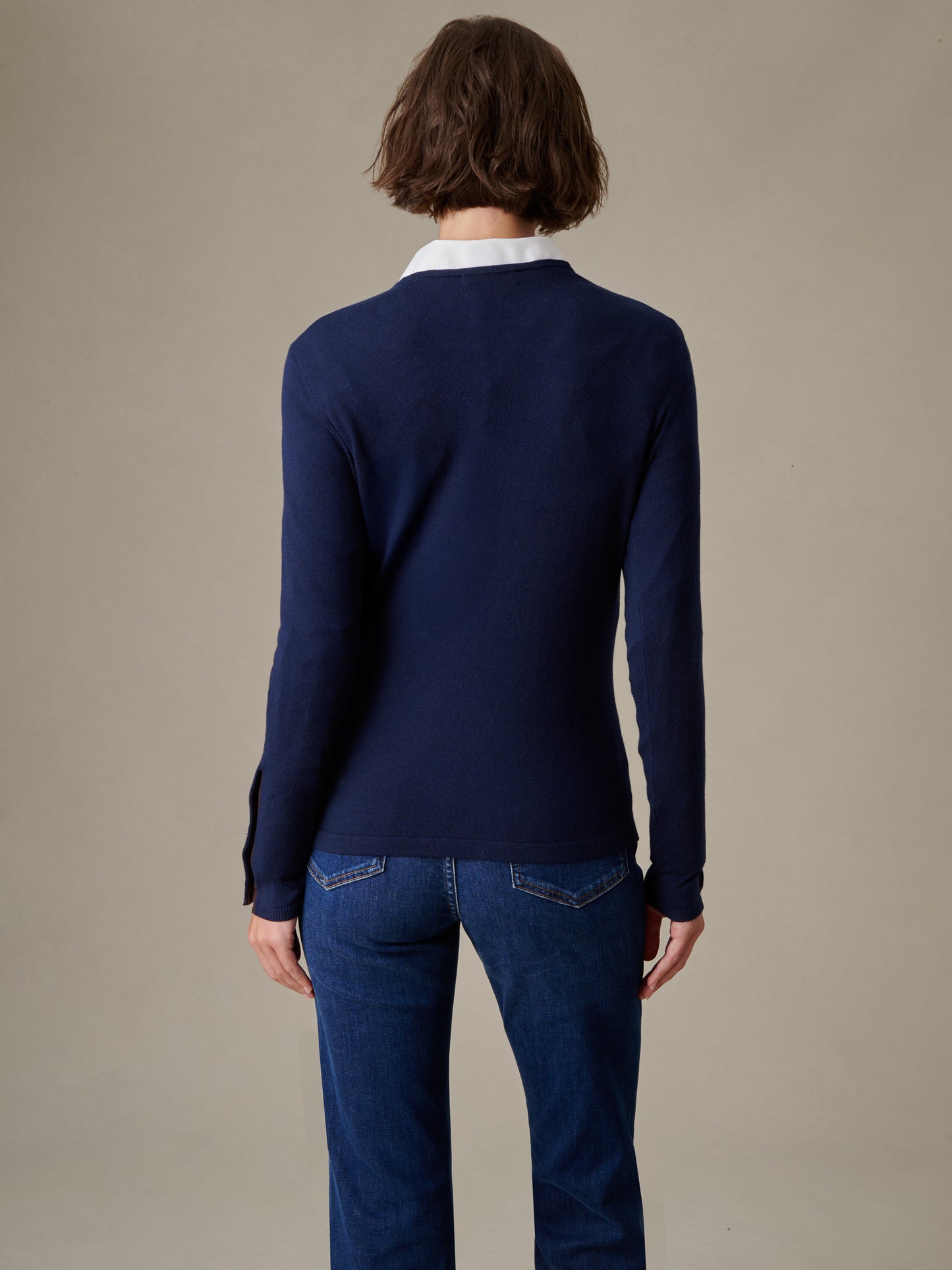 Woman wearing a navy blue Jamey Sweater by J.McLaughlin paired with blue jeans, highlighting effortlessly stylish and enduring design with timeless appeal.