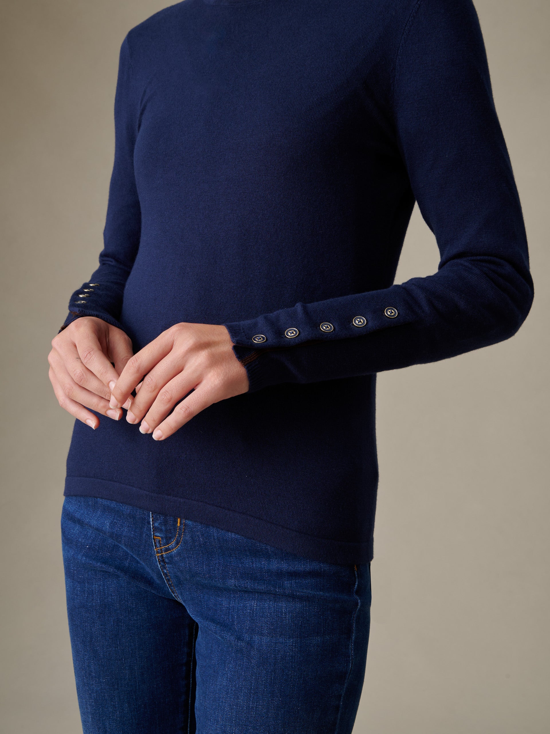 Woman wearing a navy blue Jamey Sweater by J.McLaughlin featuring button details on the sleeves, exemplifying effortlessly stylish and enduring design.