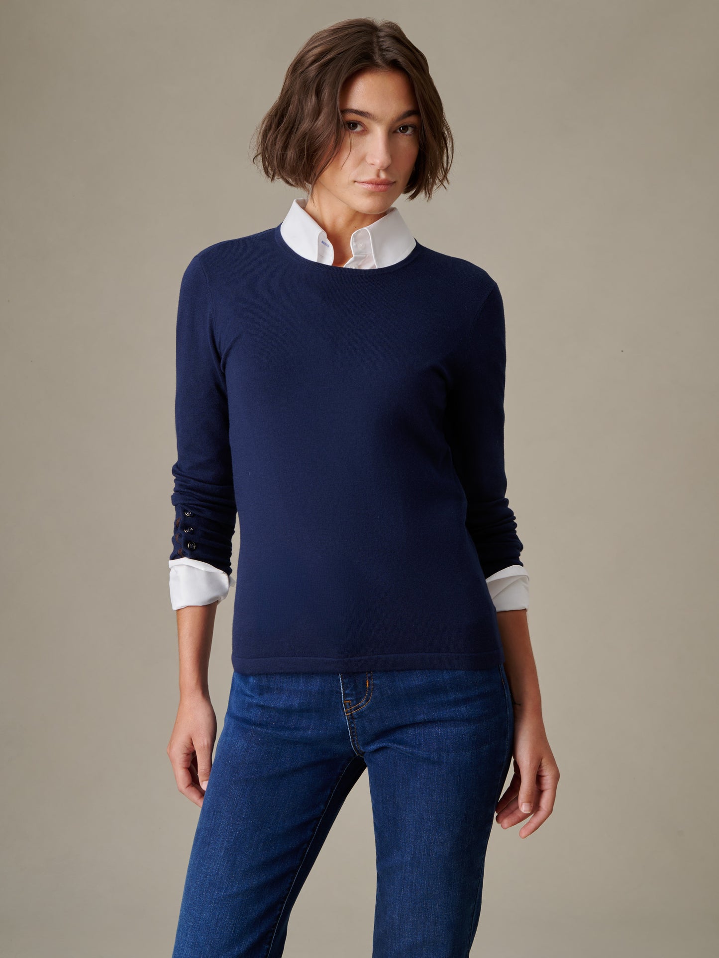 Woman wearing a navy Jamey Sweater over a white collared shirt paired with blue jeans, showcasing J.McLaughlin’s effortlessly stylish and enduring design.