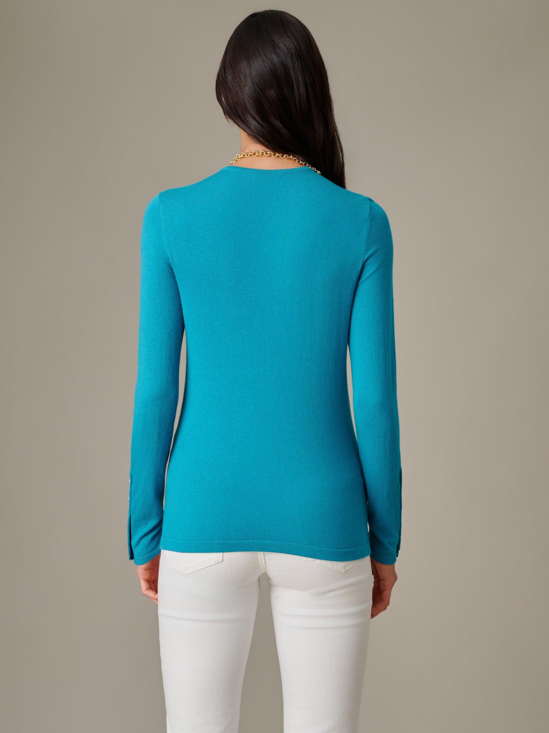 Back view of a woman wearing a vibrant blue Jamey Sweater by J.McLaughlin paired with white pants, showcasing an effortlessly stylish and classic design.
