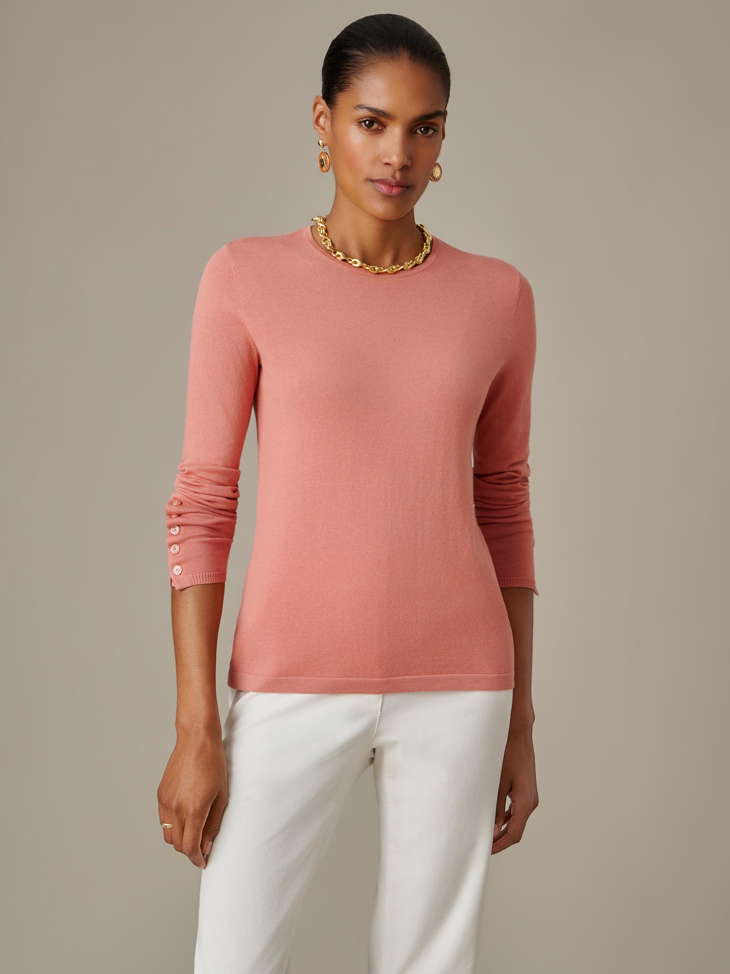 Woman wearing a soft pink Jamey Sweater by J.McLaughlin paired with white pants, showcasing timeless style and impeccable craftsmanship in a classic, enduring design.