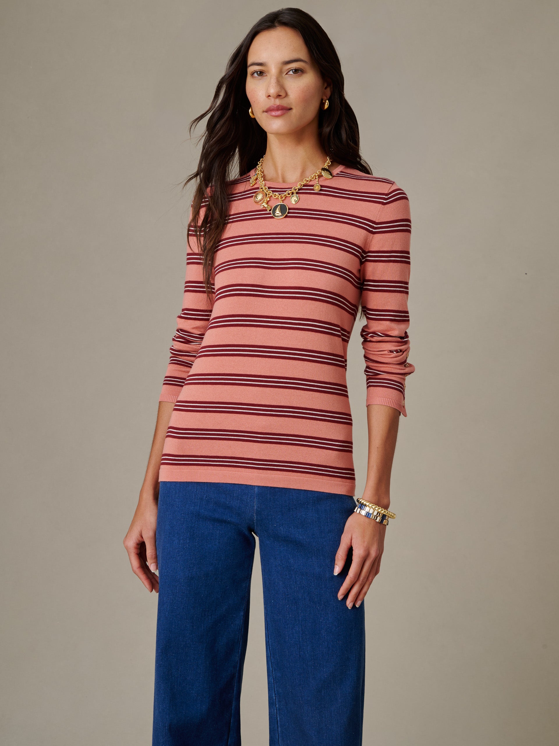 Woman wearing Jamey Sweater in Stripe by J.McLaughlin, featuring a pink and black striped pattern paired with blue jeans, styled with gold jewelry in a timeless, classic look.