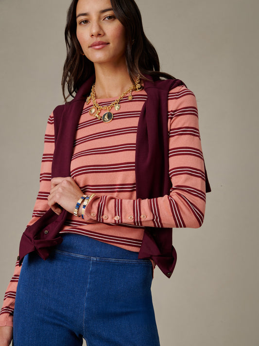 Woman wearing J.McLaughlin Jamey Sweater in Stripe layered with a burgundy sweater draped over shoulders, paired with blue jeans and gold jewelry for an effortlessly stylish look.