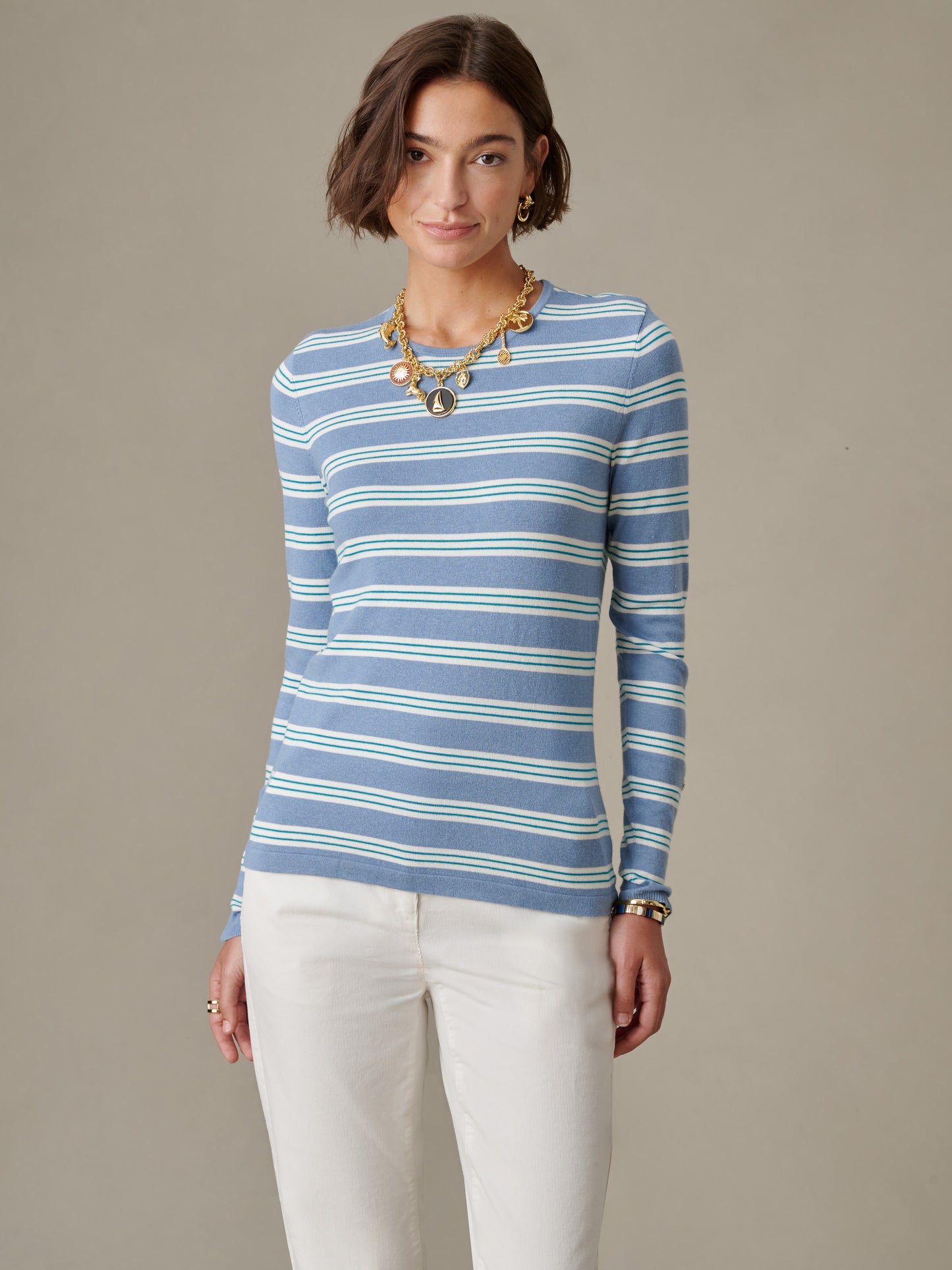 Woman wearing a blue and white striped Jamey Sweater in Stripe by J.McLaughlin paired with white pants and gold jewelry, showcasing a timeless, effortlessly stylish look.