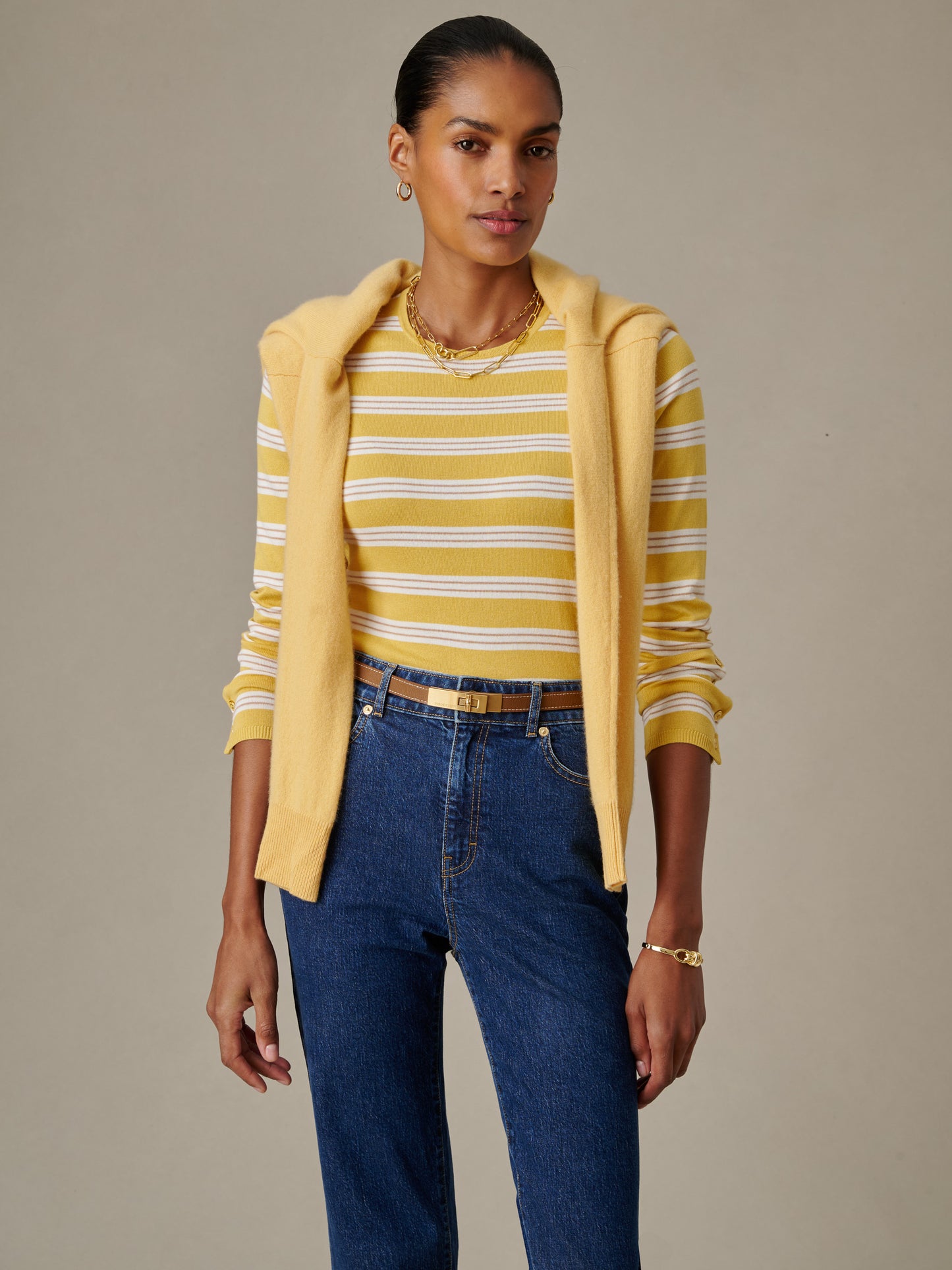 Woman wearing Jamey Sweater in Stripe by J.McLaughlin paired with denim jeans and a yellow sweater draped over shoulders, showcasing timeless style and craftsmanship.
