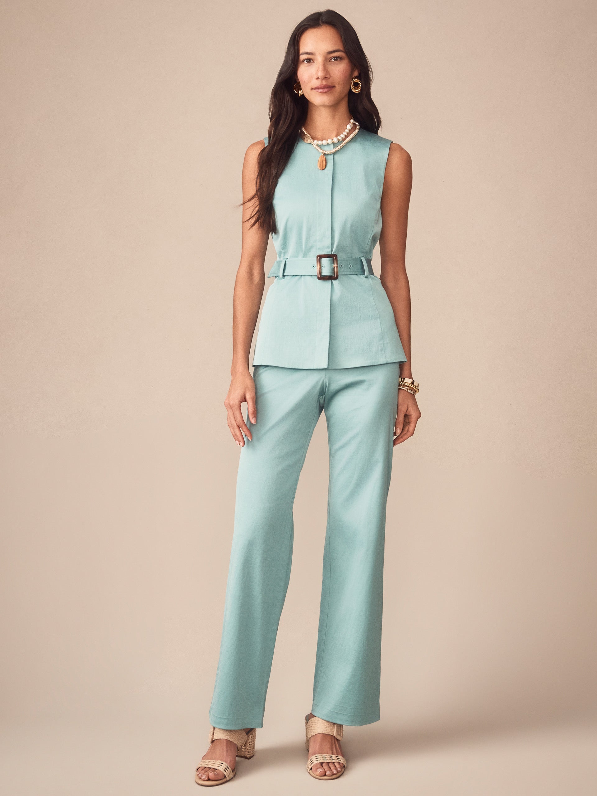 Woman wearing J.McLaughlin Carter Dupioni Cotton Pants in seafoam, styled with a sleeveless belted top and layered necklaces, showcasing effortlessly stylish, enduring designs.