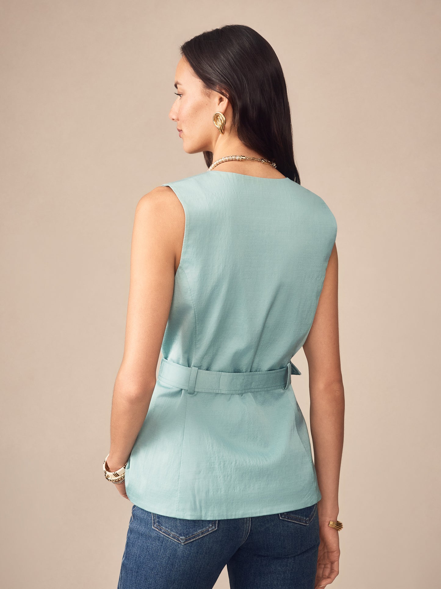 Woman wearing a seafoam green Jennifer Dupioni Cotton Vest by J.McLaughlin, styled with blue jeans, showcasing effortlessly stylish, enduring designs and innovative fabrics.