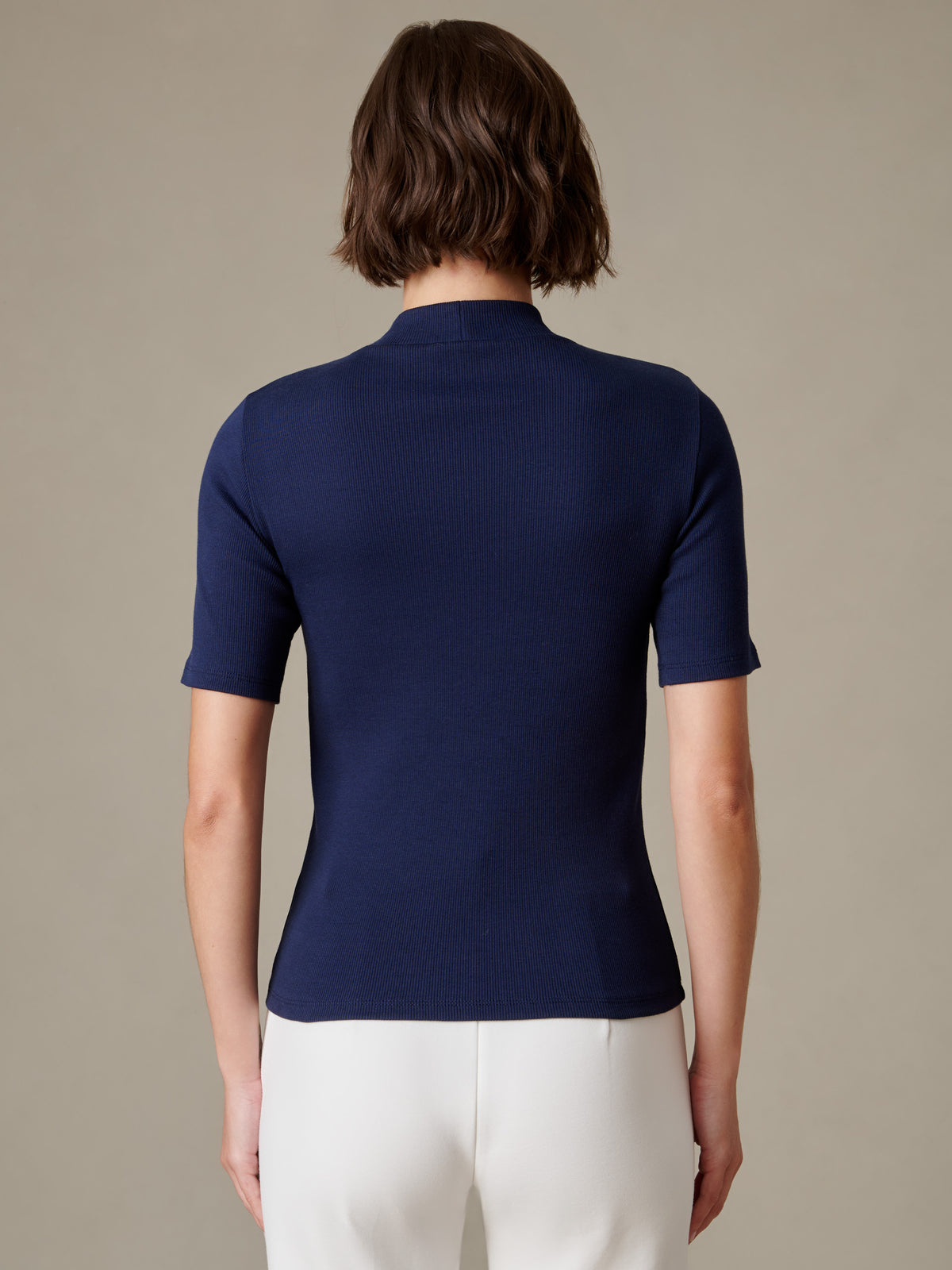 J.McLaughlin Jess Ribbed Top shown from the back on a model featuring a navy ribbed mock neckline short sleeves and a flattering fitted silhouette
