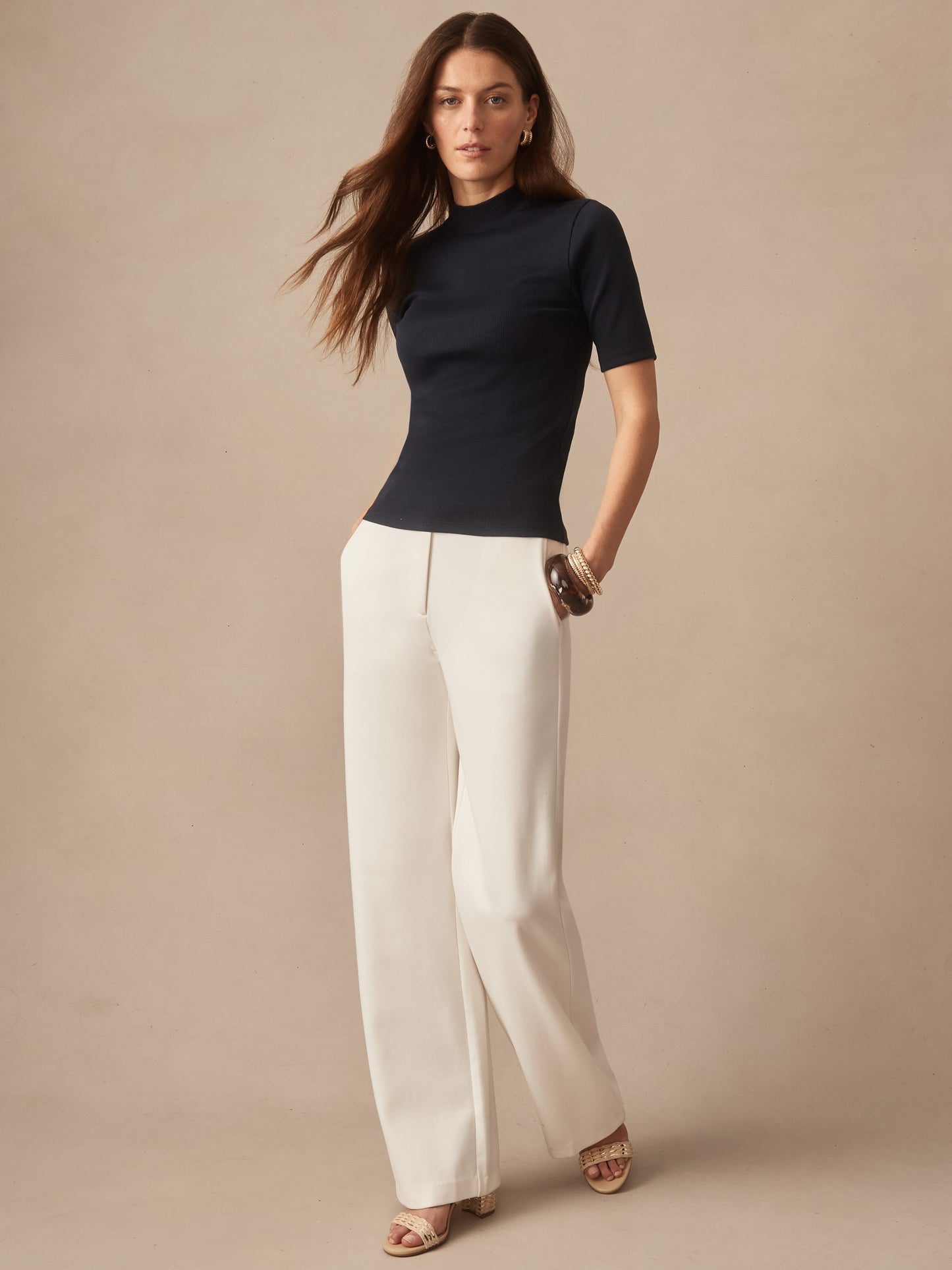 Woman wearing a navy Jess Ribbed Top by J.McLaughlin paired with cream wide-leg pants, showcasing effortlessly stylish, enduring designs with innovative fabrics and a legacy of timeless fashion. A destination for defining style. Life, Well-Lived.