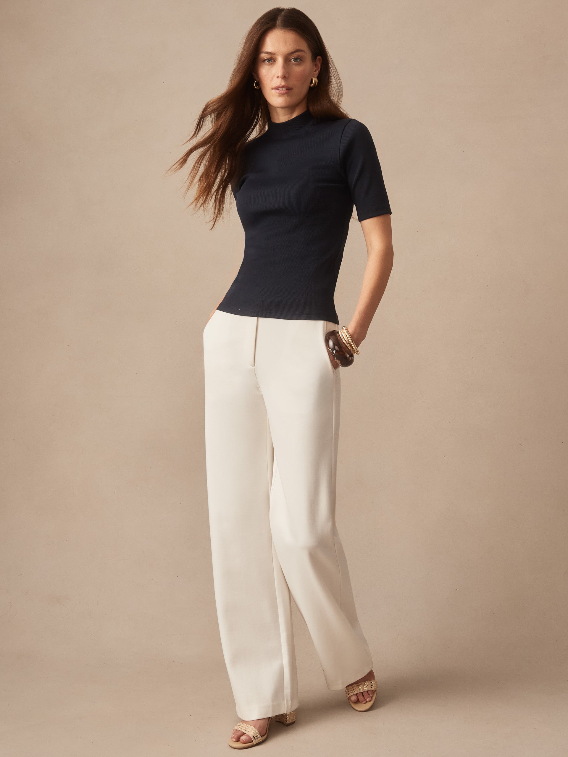 Woman wearing a navy Jess Ribbed Top by J.McLaughlin paired with cream wide-leg pants, showcasing effortlessly stylish, enduring designs with innovative fabrics and a legacy of timeless fashion. A destination for defining style. Life, Well-Lived.