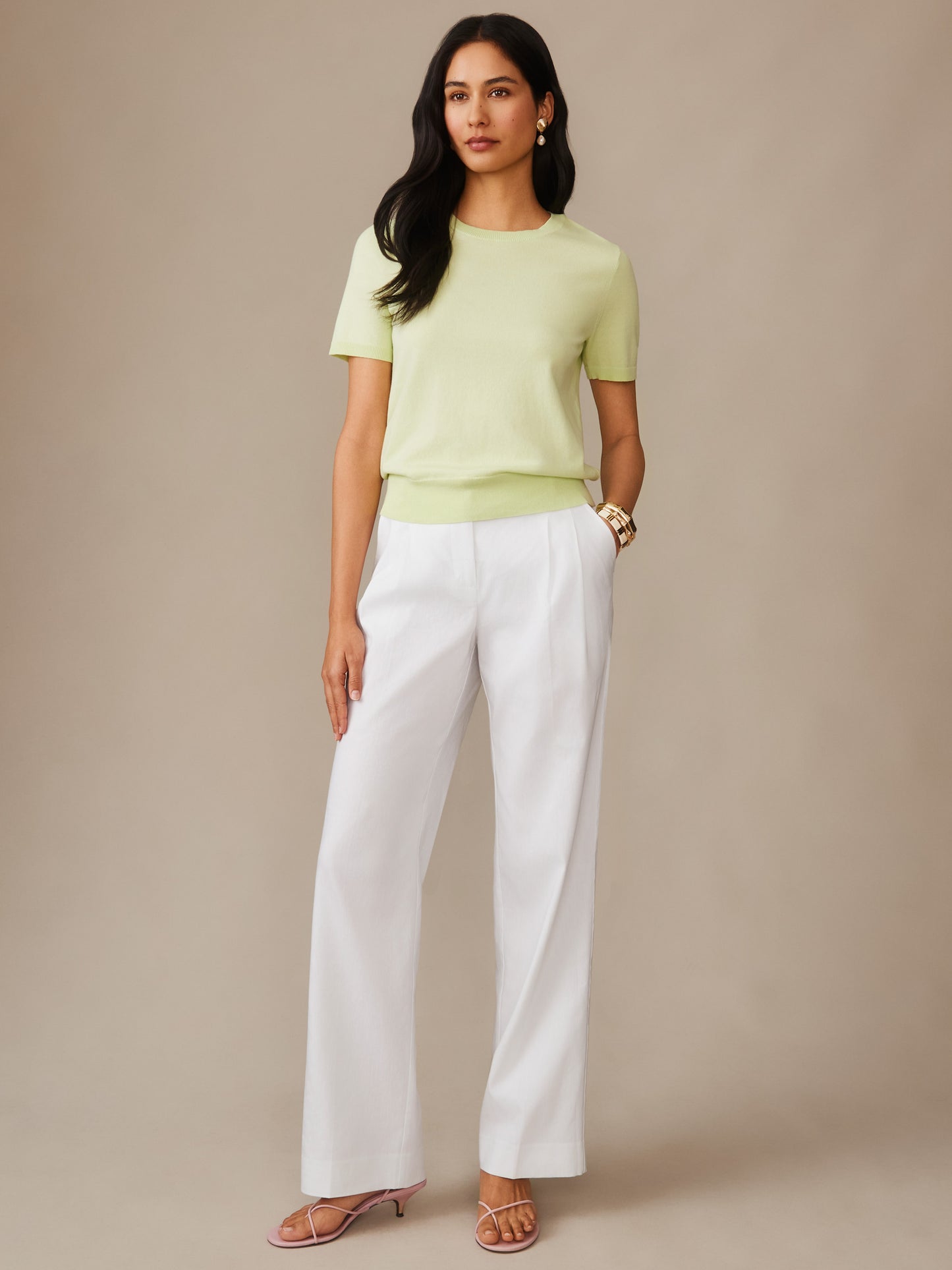 Woman wearing a light green Joelle Sweater by J.McLaughlin paired with white pants, showcasing effortlessly stylish, enduring designs in innovative fabrics. A destination for defining style. Life, Well-Lived.