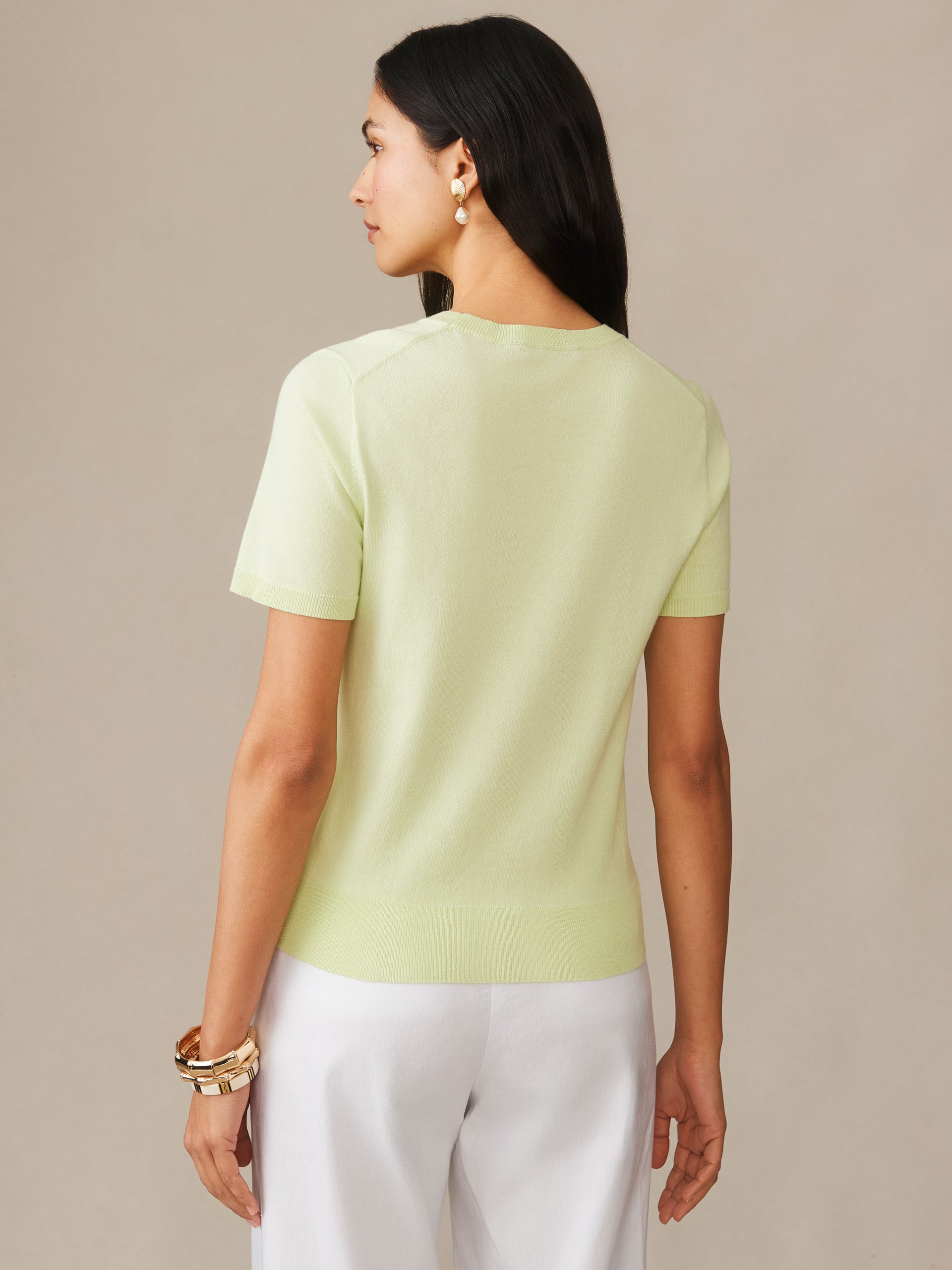 A woman wearing a light celery Joelle Sweater by J.McLaughlin, showcasing an effortlessly stylish and enduring design crafted with innovative fabrics for a legacy of timeless fashion.