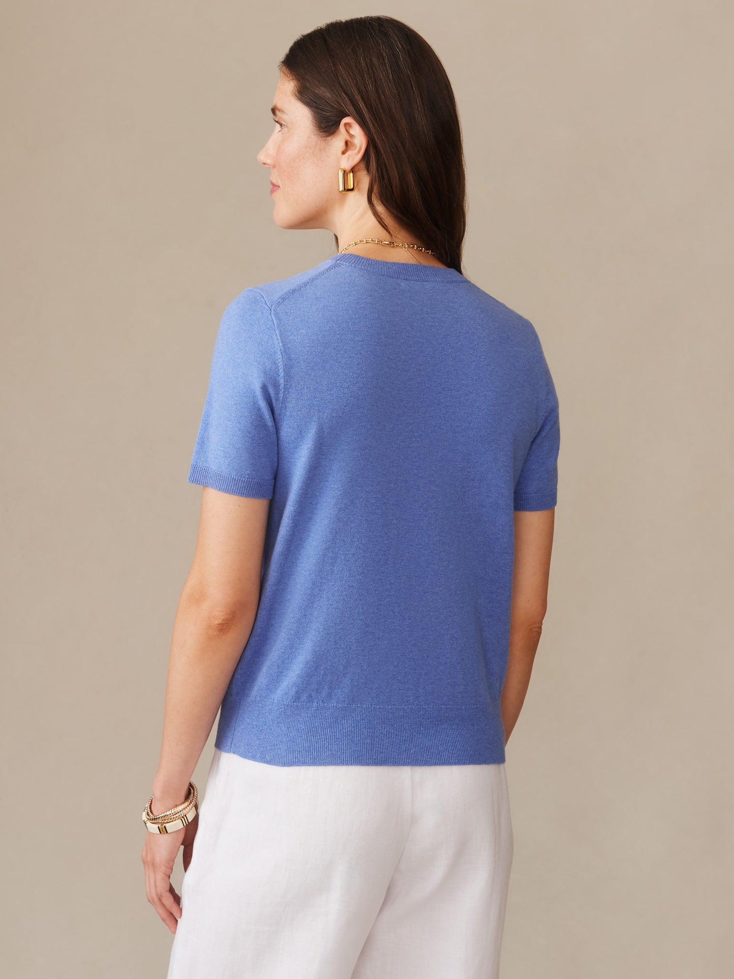 Woman wearing a lapis blue Joelle Sweater by J. McLaughlin, showcasing effortlessly stylish short sleeves and enduring design, perfect for timeless, well-lived fashion.