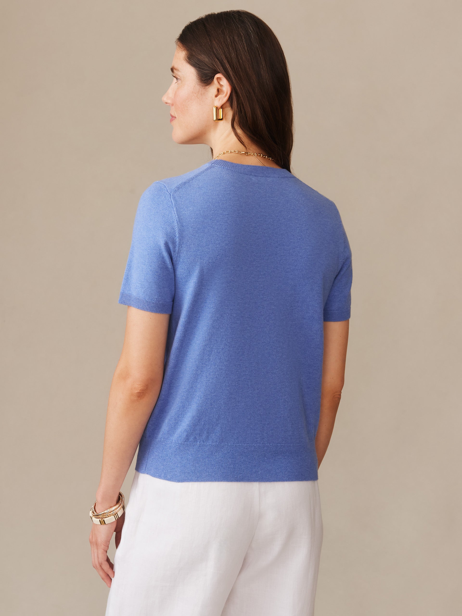 Woman wearing a lapis blue Joelle Sweater by J. McLaughlin, showcasing effortlessly stylish short sleeves and enduring design, perfect for timeless, well-lived fashion.