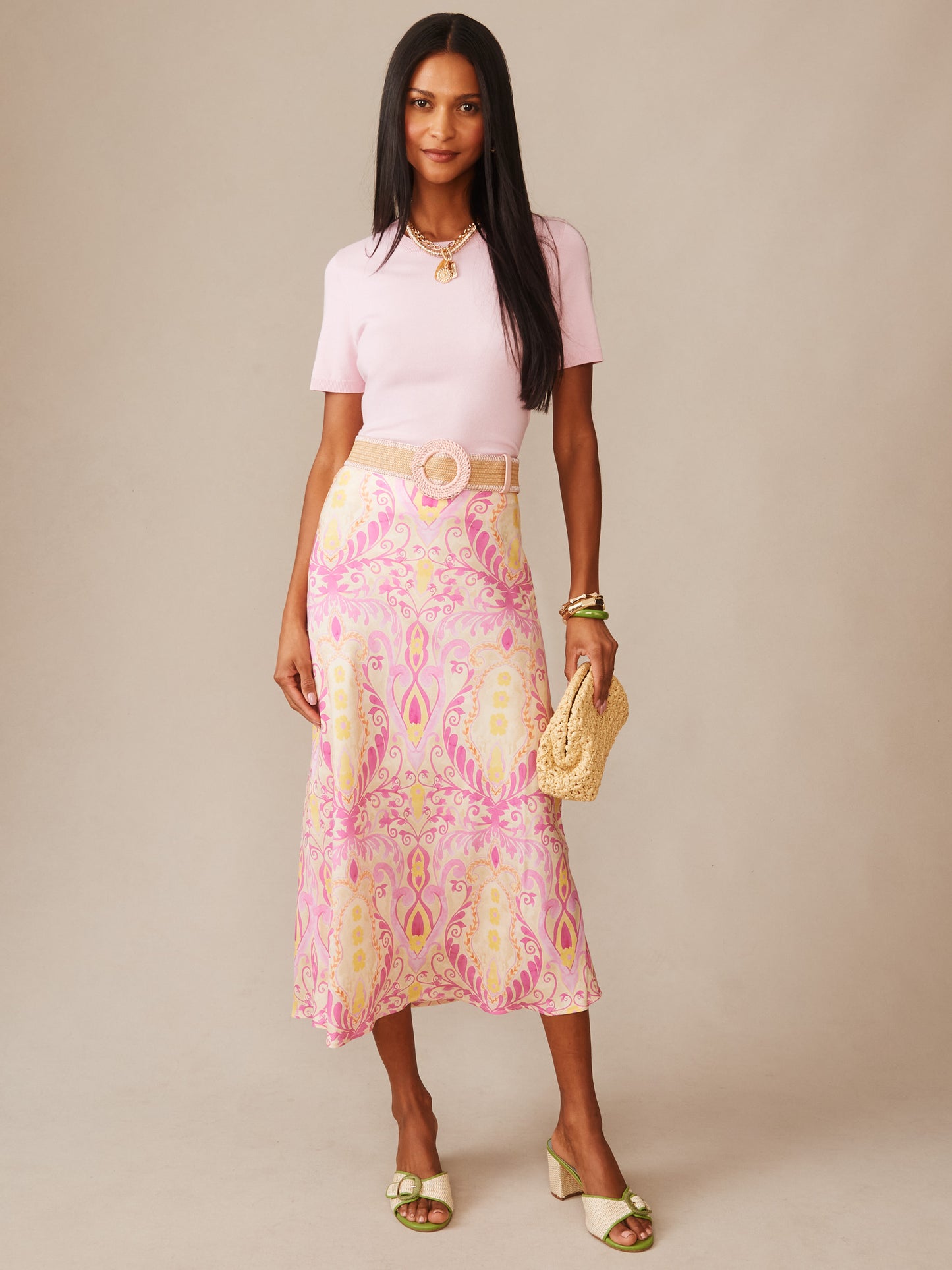Woman wearing a pink top paired with the Adelyn Silk Blend Skirt in Mini Deco Bloom Bias by J.McLaughlin, featuring a floral pattern in soft pink and cream tones, styled with a woven belt and natural accessories, showcasing effortlessly stylish, enduring designs with innovative fabrics in a legacy of timeless fashion. A destination for defining style. Life, Well-Lived.