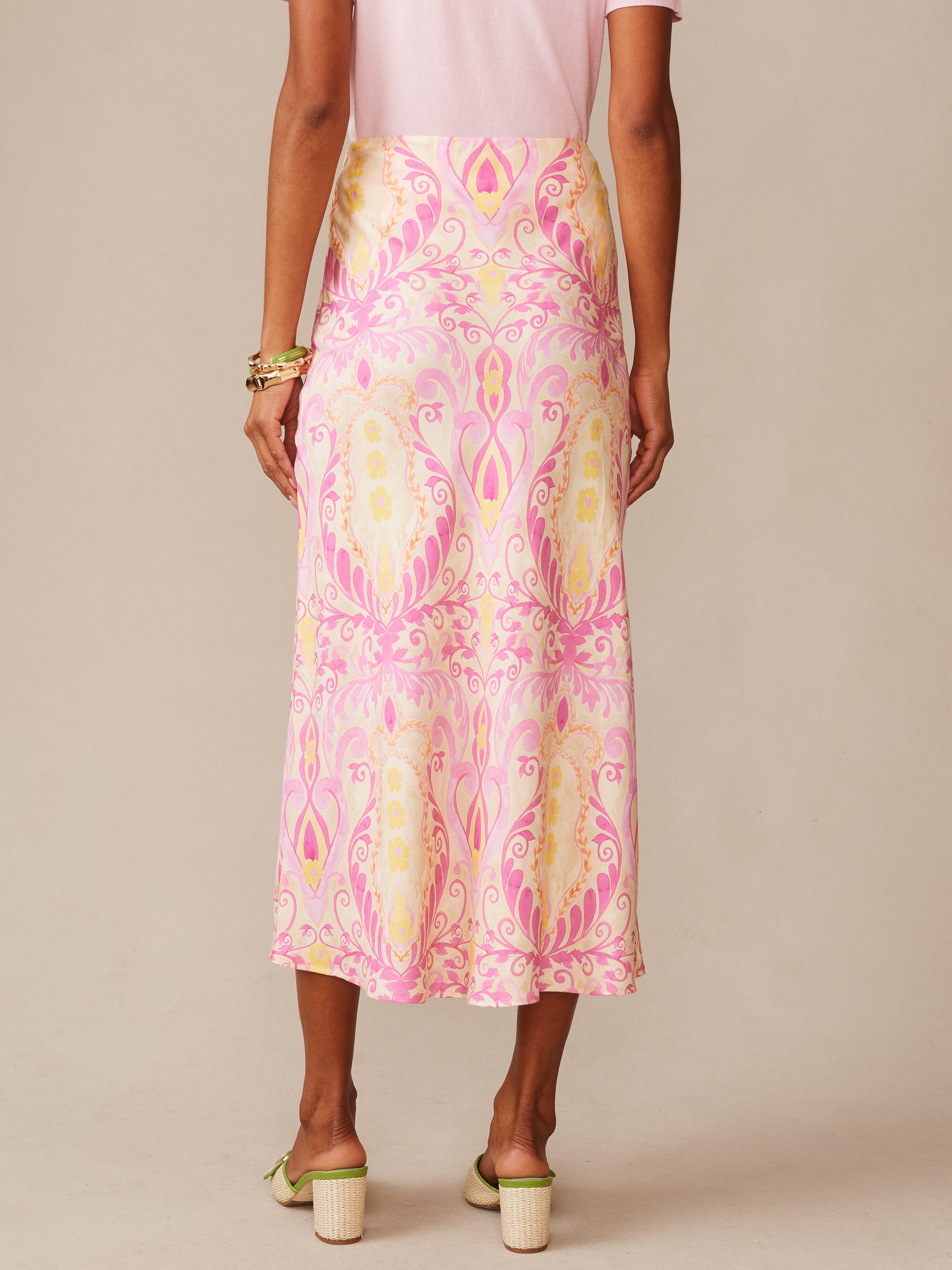 Woman wearing an Adelyn Silk Blend Skirt in Mini Deco Bloom Bias by J.McLaughlin, featuring a pink and cream floral pattern paired with heels, showcasing effortlessly stylish, enduring designs and innovative fabrics in a legacy of timeless fashion. A destination for defining style. Life, Well-Lived.