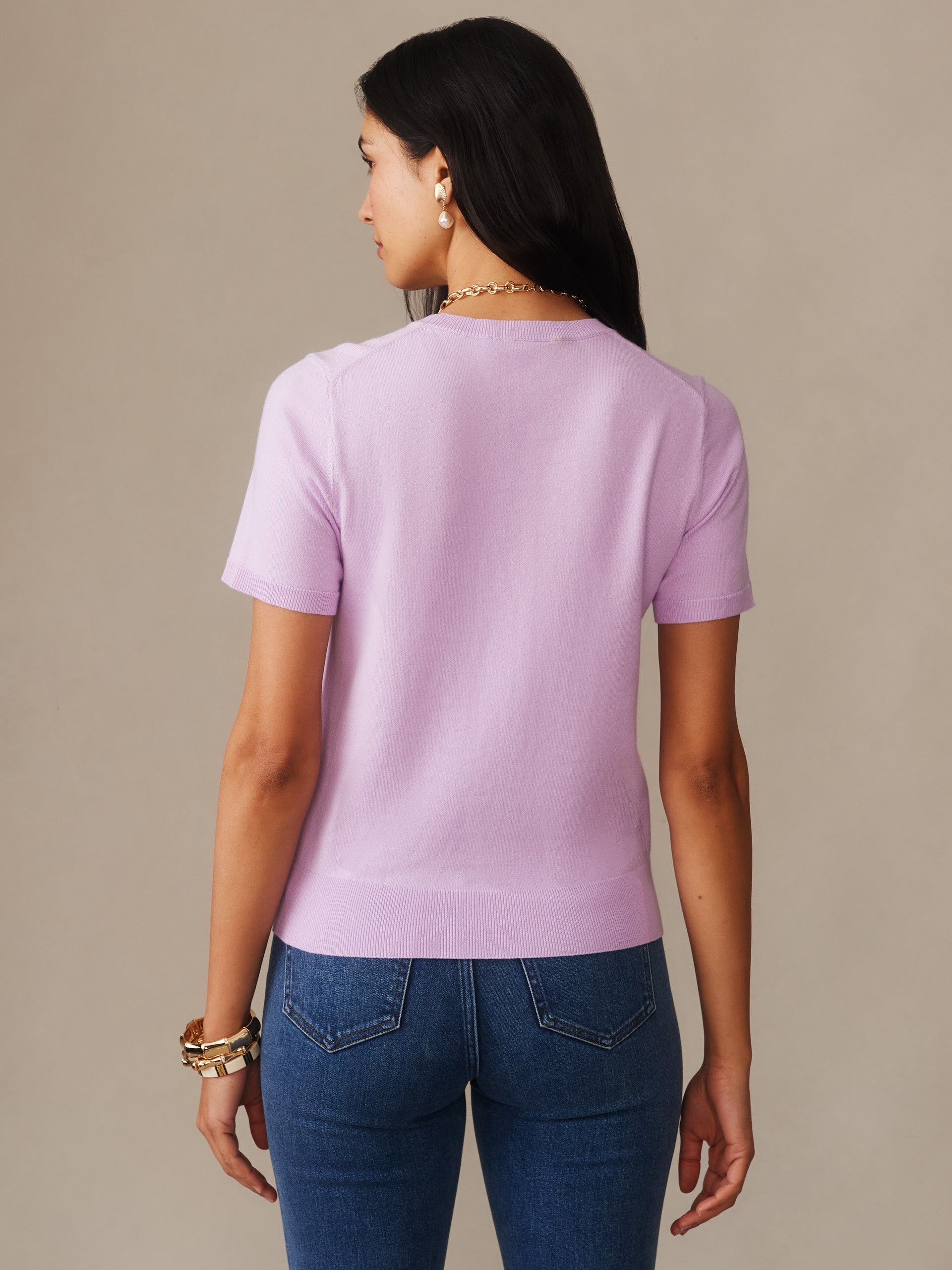 A woman wearing the Joelle Sweater by J.McLaughlin in a soft wisteria hue, showcasing effortlessly stylish design and enduring craftsmanship for a destination defining style. Life, Well-Lived.