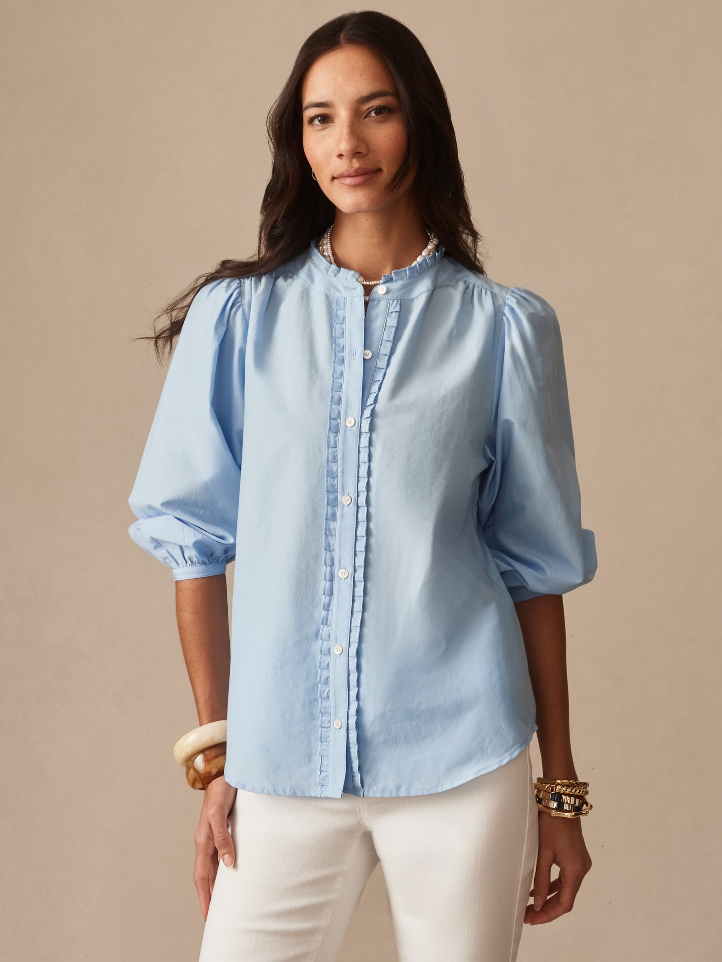 Woman wearing a light blue Josette Blouse by J.McLaughlin featuring puff sleeves and delicate button detailing, showcasing effortlessly stylish, enduring designs in innovative fabrics.
