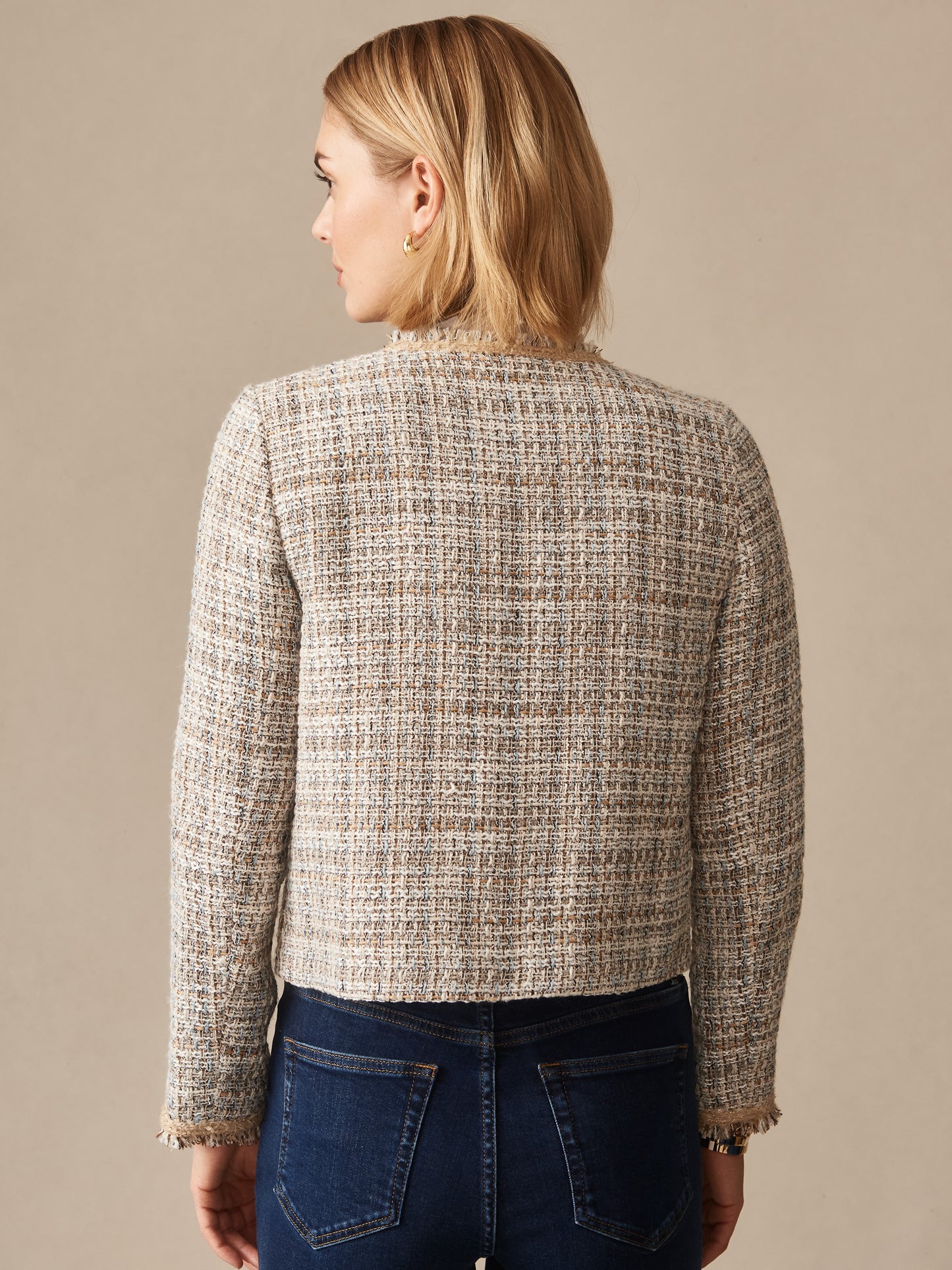 Woman seen from behind wearing a taupe Martha Tweed Jacket by J.McLaughlin, paired with dark jeans, showcasing effortlessly stylish, enduring designs and innovative fabrics.