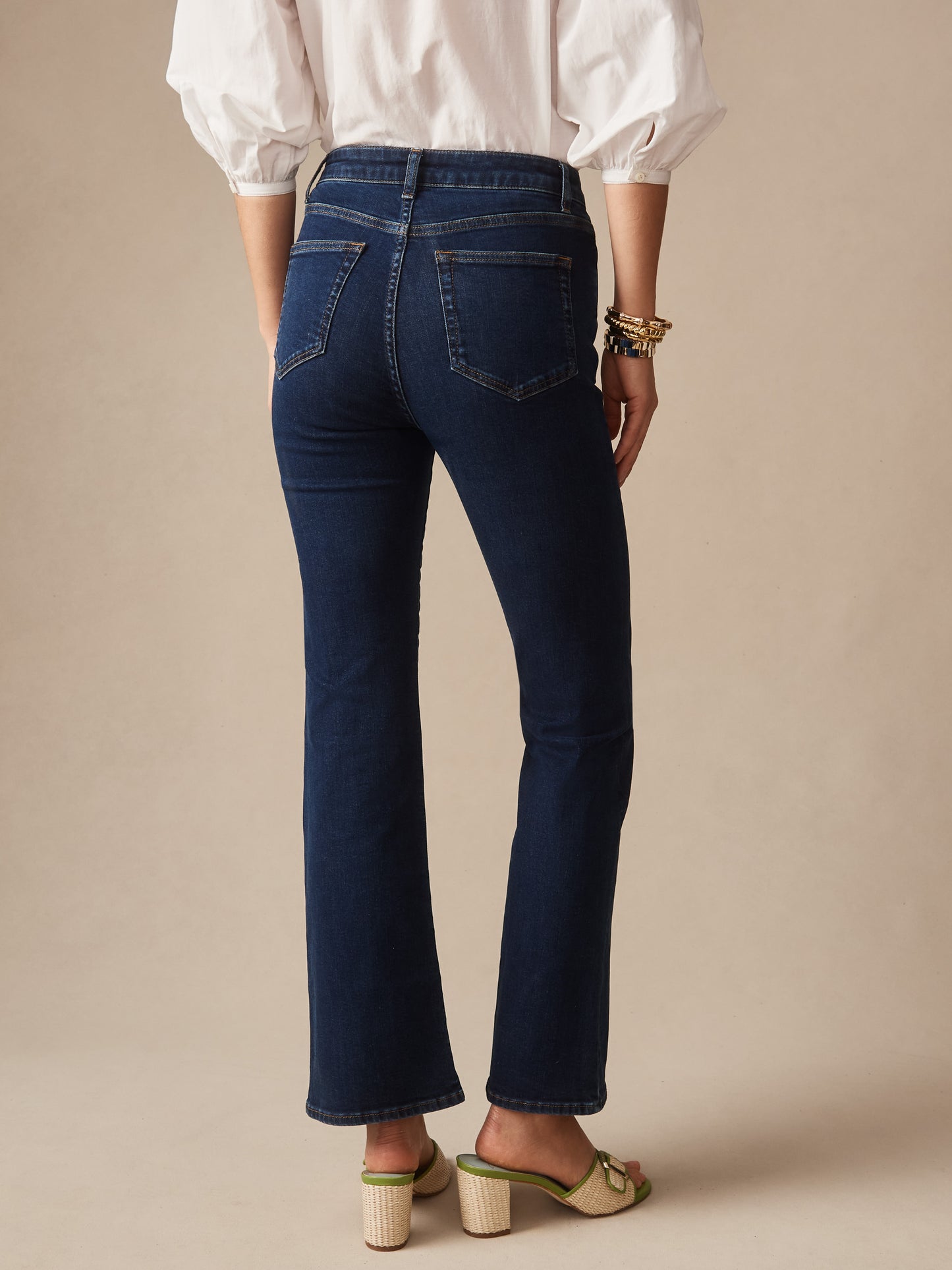 Back view of a person wearing dark blue Elvira Jeans by J.McLaughlin paired with a white blouse and beige heels, showcasing effortlessly stylish, enduring designs and innovative fabrics.