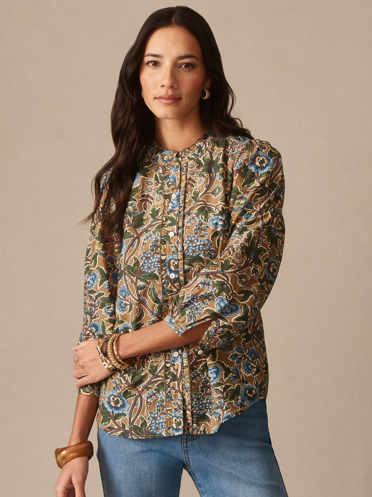 Woman wearing Josette Blouse in Bucolic Blooms by J.McLaughlin featuring a floral pattern in earthy tones, styled with blue jeans and elegant accessories, showcasing effortlessly stylish, enduring designs. A destination for defining style. Life, Well-Lived.