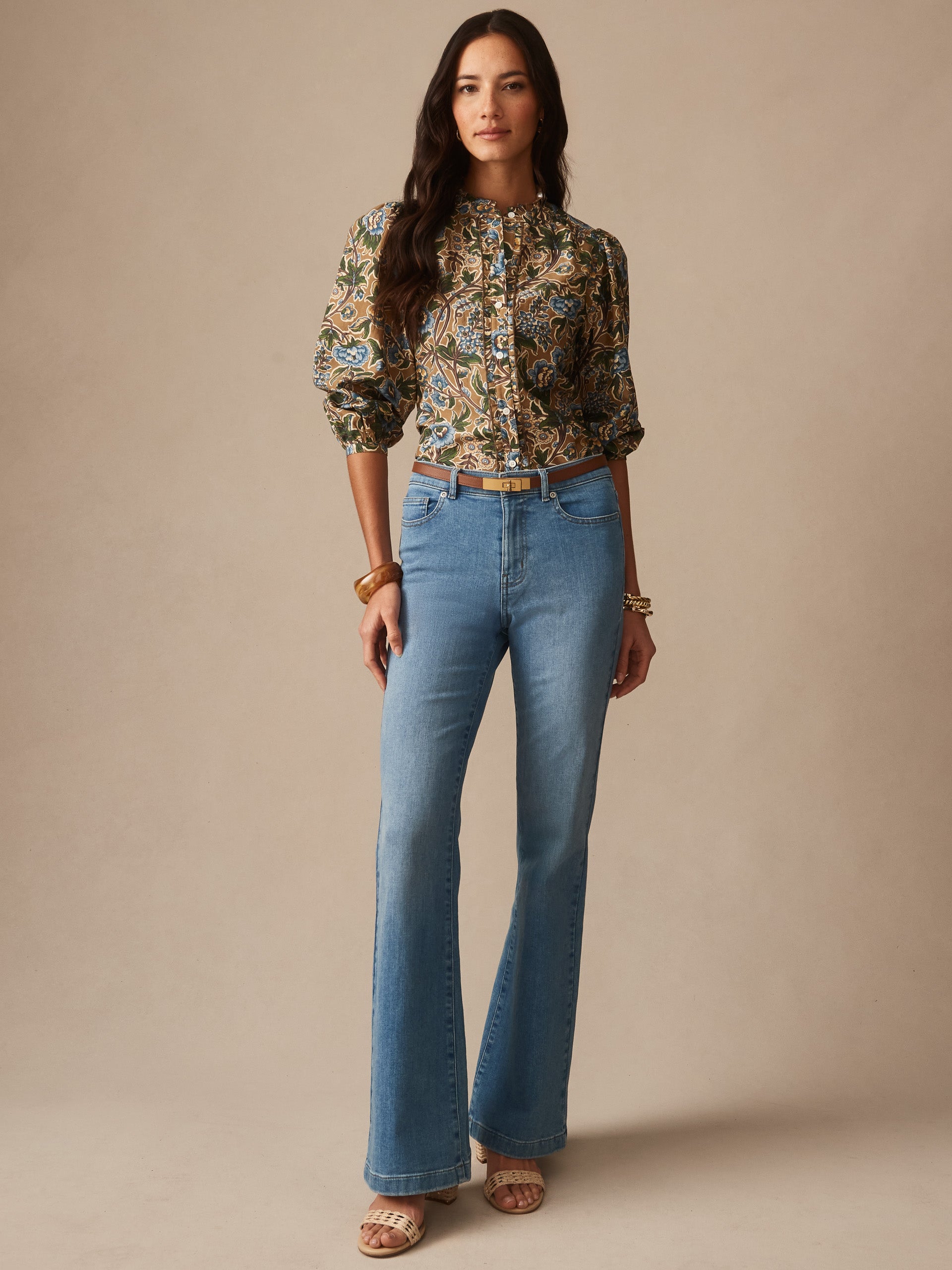 Model wearing Josette Blouse in Bucolic Blooms by J.McLaughlin, paired with high-waisted flared jeans and sandals, showcasing effortlessly stylish, enduring designs for a life well-lived.
